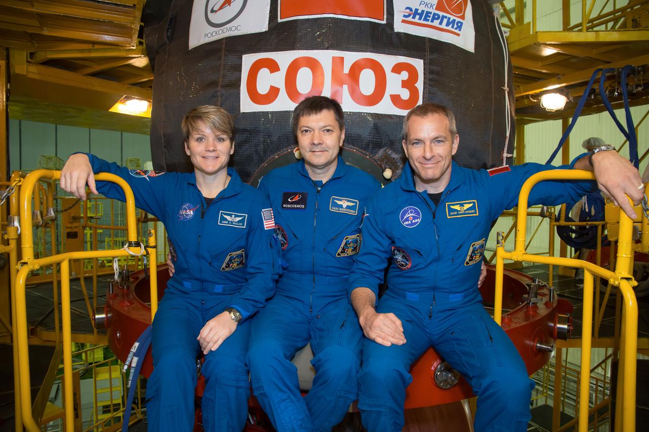 jsc2018e097285 - In the Integration Facility at the Baikonur Cosmodrome in Kazakhstan, Expedition 58 crewmembers Anne McClain of NASA (left), Oleg Kononenko of Roscosmos (center) and David Saint-Jacques of the Canadian Space Agency (right) pose for pictures Nov. 20 in front of their Soyuz MS-11 spacecraft during a vehicle fit check. They will launch Dec. 3 on the Soyuz MS-11 spacecraft from the Baikonur Cosmodrome for a six-and-a-half month mission on the International Space Station...NASA/Victor Zelentsov.