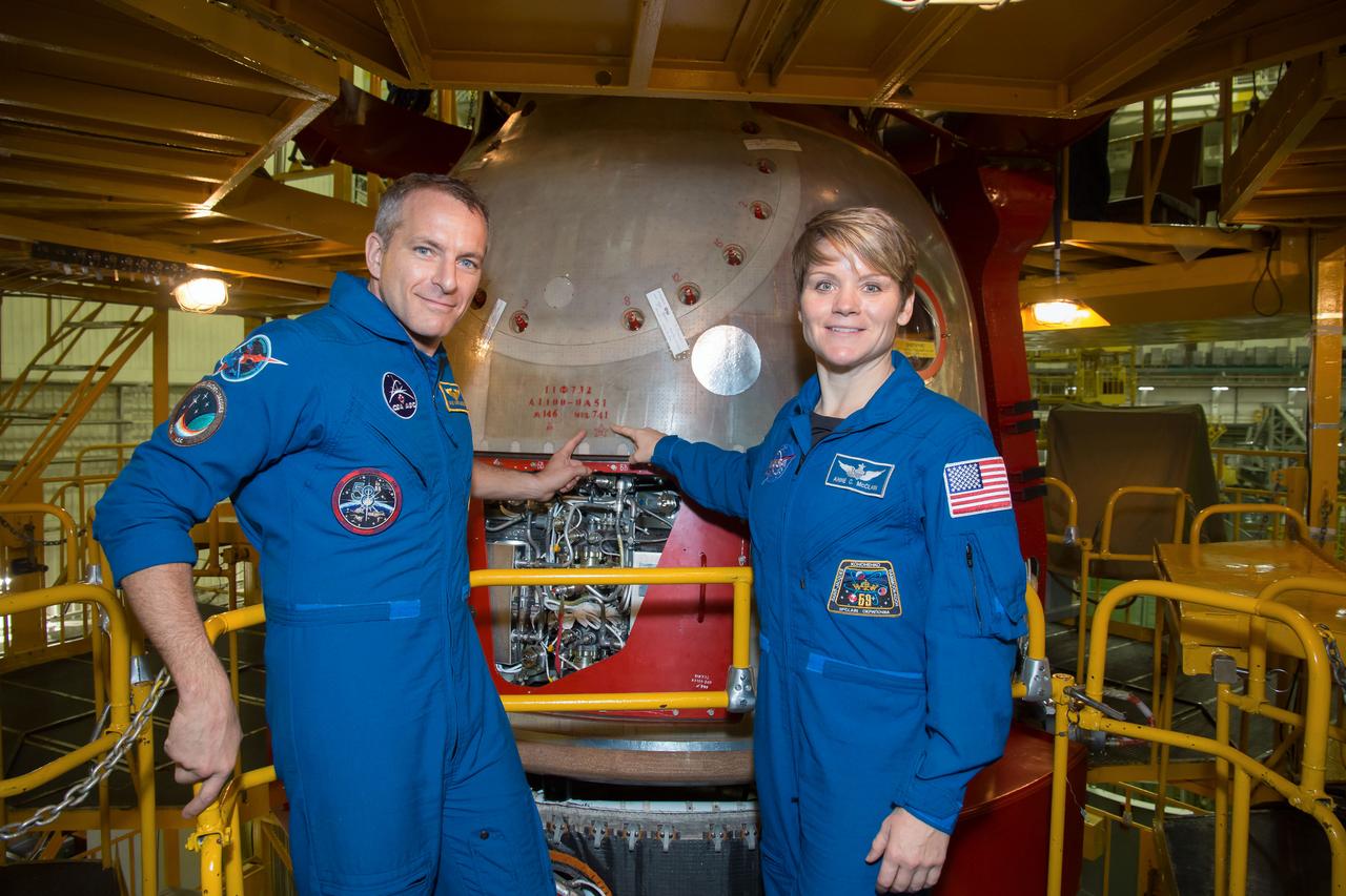jsc2018e097289 - In the Integration Facility at the Baikonur Cosmodrome in Kazakhstan, Expedition 58 crewmembers David Saint-Jacques of the Canadian Space Agency (left) and Anne McClain of NASA (right) point to the serial number of their Soyuz spacecraft Nov. 20 during a vehicle fit check. Saint-Jacques, McClain and Oleg Kononenko of Roscosmos will launch Dec. 3 on the Soyuz MS-11 spacecraft from the Baikonur Cosmodrome for a six-and-a-half month mission on the International Space Station...NASA/Victor Zelentsov.
