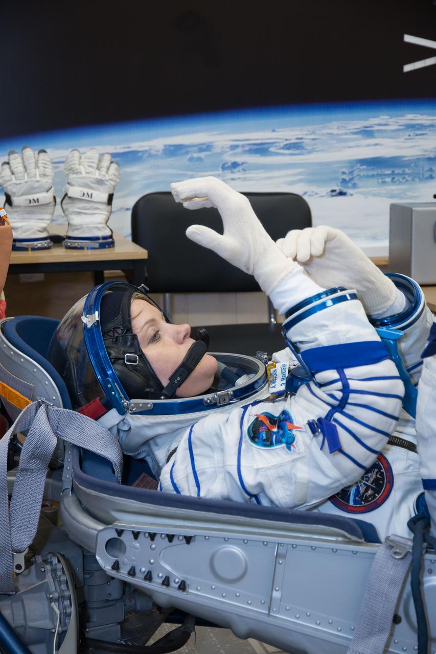 jsc2018e097295 - In the Integration Facility at the Baikonur Cosmodrome in Kazakhstan, Expedition 58 crewmember Anne McClain of NASA tries on gloves Nov. 20 during a Russian Sokol launch and entry suit pressure and leak check. McClain, Oleg Kononenko of Roscosmos and David Saint-Jacques of the Canadian Space Agency will launch Dec. 3 on the Soyuz MS-11 spacecraft from the Baikonur Cosmodrome for a six-and-a-half month mission on the International Space Station...NASA/Victor Zelentsov.
