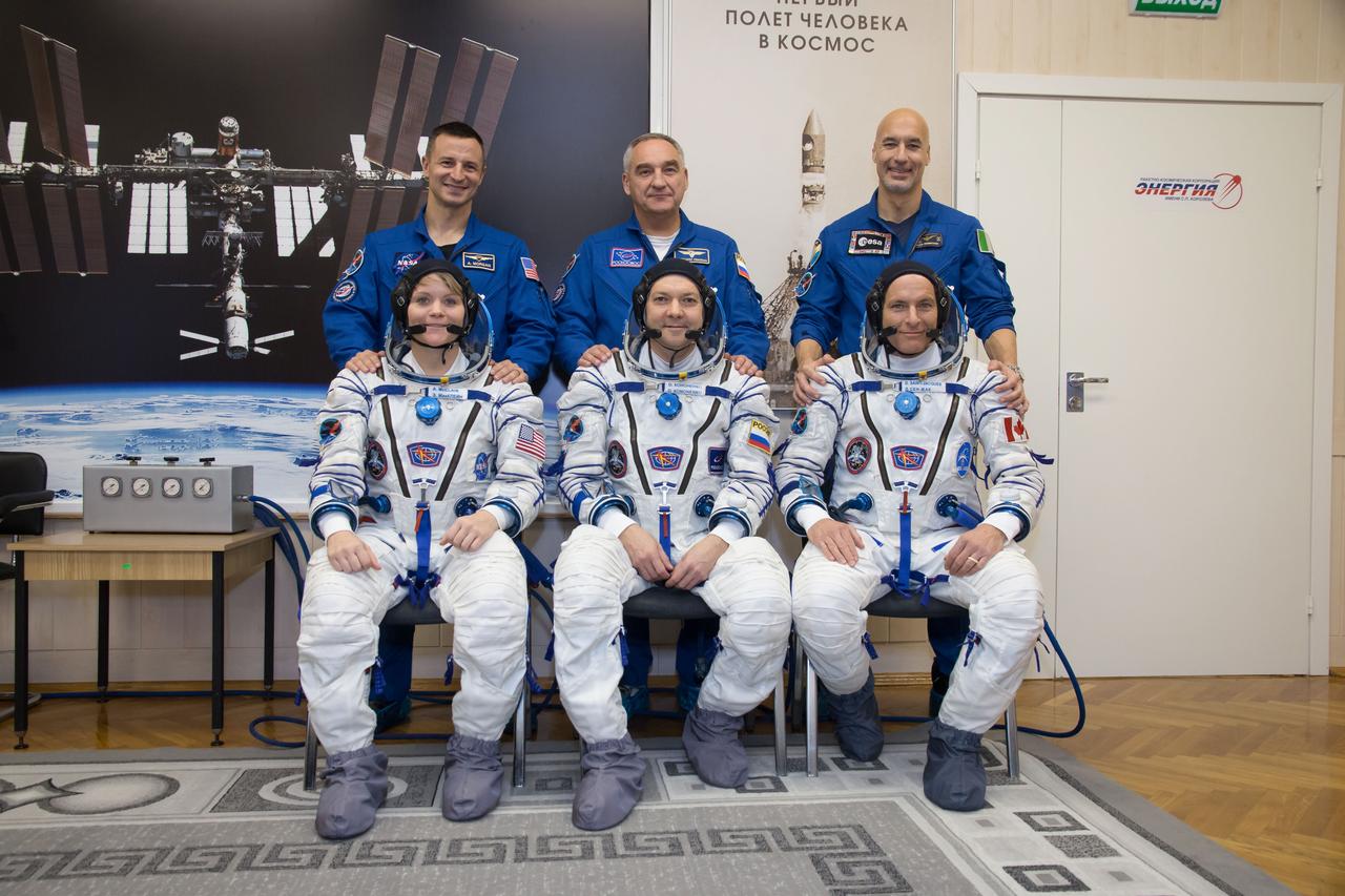jsc2018e097298 - In the Integration Facility at the Baikonur Cosmodrome in Kazakhstan, Expedition 58 crewmembers Anne McClain of NASA (front row, left), Oleg Kononenko of Roscosmos (front row, center) and David Saint-Jacques of the Canadian Space Agency (front row, right) pose for pictures Nov. 20 during their vehicle fit check activities. Behind them are their backups, Drew Morgan of NASA (left), Alexander Skvortsov of Roscosmos (center) and Luca Parmitano of the European Space Agency (right). McClain, Kononenko and Saint-Jacques will launch Dec. 3 on the Soyuz MS-11 spacecraft from the Baikonur Cosmodrome for a six-and-a-half month mission on the International Space Station...NASA/Victor Zelentsov.