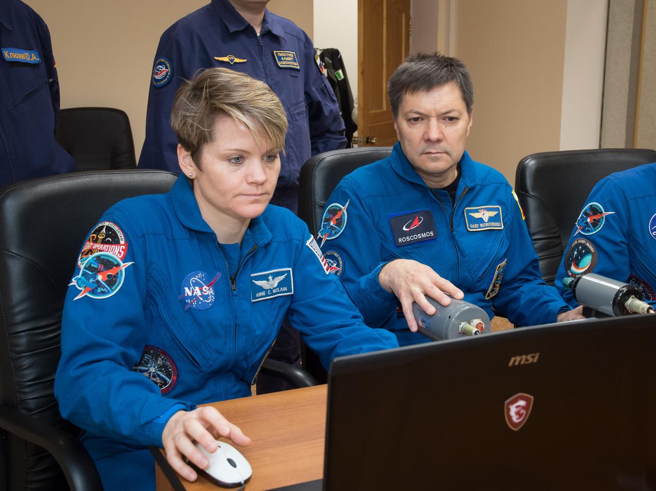 jsc2018e097761 - At their Cosmonaut Hotel crew quarters in Baikonur, Kazakhstan, Expedition 58 crewmembers Anne McClain of NASA (left) and Oleg Kononenko of Roscosmos (right) practice rendezvous techniques on a laptop computer Nov. 27 as part of their pre-launch training. McClain, Kononenko and David Saint-Jacques of the Canadian Space Agency will launch Dec. 3 on the Soyuz MS-11 spacecraft from the Baikonur Cosmodrome in Kazakhstan for a six-and-a-half month mission on the International Space Station...NASA/Victor Zelentsov.
