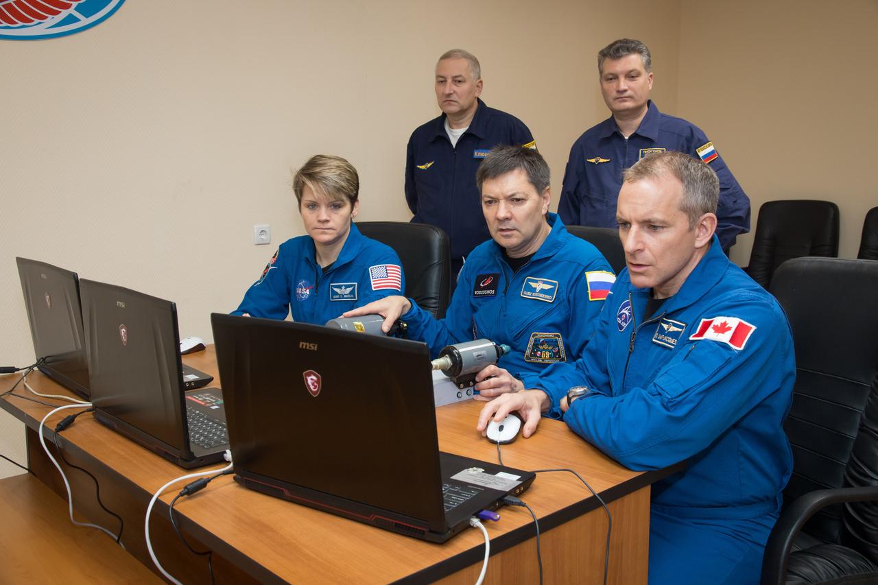 jsc2018e097762 - At their Cosmonaut Hotel crew quarters in Baikonur, Kazakhstan, Expedition 58 crewmembers Anne McClain of NASA (left), Oleg Kononenko of Roscosmos (center) and David Saint-Jacques of the Canadian Space Agency (right) practice rendezvous techniques on a laptop computer Nov. 27 as part of their pre-launch training. They will launch Dec. 3 on the Soyuz MS-11 spacecraft from the Baikonur Cosmodrome in Kazakhstan for a six-and-a-half month mission on the International Space Station...NASA/Victor Zelentsov.