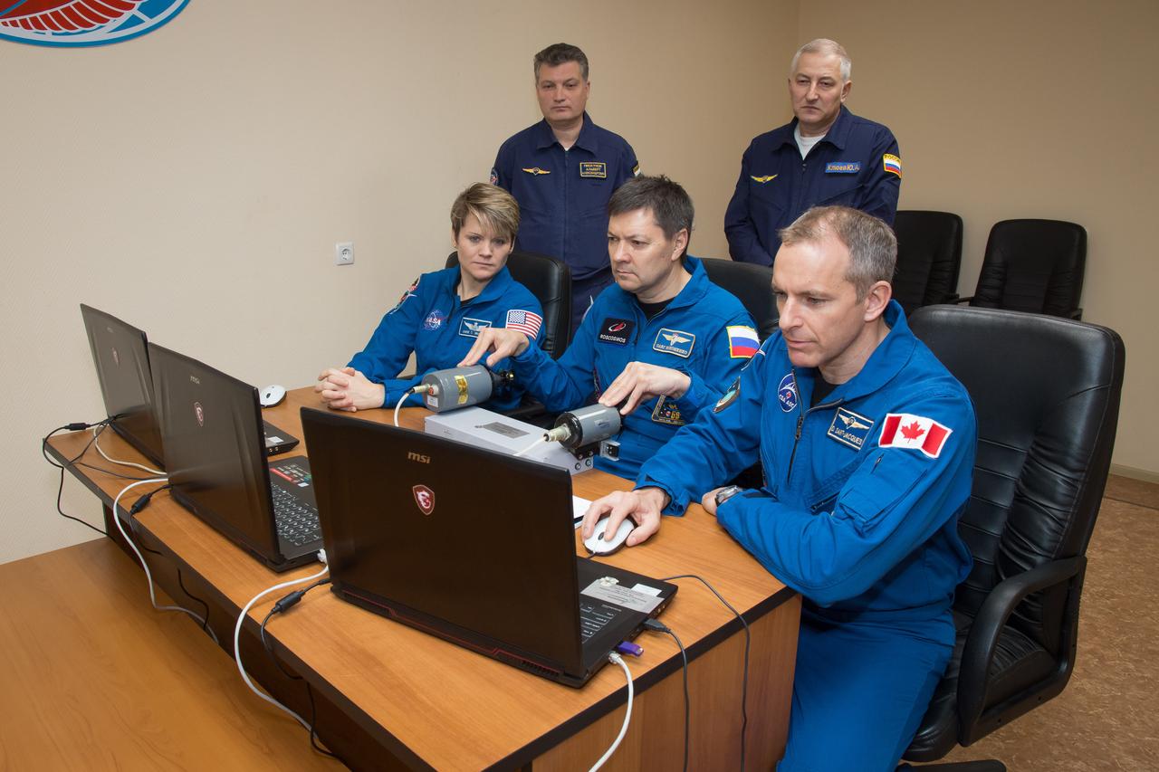 jsc2018e097765 - At their Cosmonaut Hotel crew quarters in Baikonur, Kazakhstan, Expedition 58 crewmembers Anne McClain of NASA (left), Oleg Kononenko of Roscosmos (center) and David Saint-Jacques of the Canadian Space Agency (right) practice rendezvous techniques on a laptop computer Nov. 27 as part of their pre-launch training. They will launch Dec. 3 on the Soyuz MS-11 spacecraft from the Baikonur Cosmodrome in Kazakhstan for a six-and-a-half month mission on the International Space Station...NASA/Victor Zelentsov.