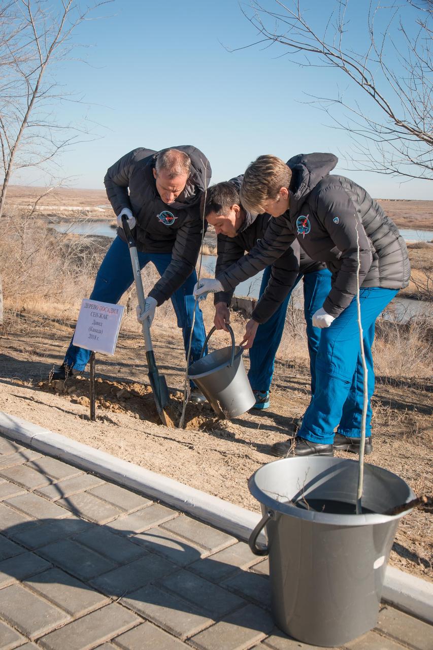 jsc2018e097776 - At their Cosmonaut Hotel crew quarters in Baikonur, Kazakhstan, Expedition 58 crewmembers David Saint-Jacques of the Canadian Space Agency (left), Oleg Kononenko of Roscosmos (center) and Anne McClain of NASA (right) plant a tree in Saint-Jacques’ name Nov. 27 as part of traditional pre-launch activities. They will launch Dec. 3 on the Soyuz MS-11 spacecraft from the Baikonur Cosmodrome in Kazakhstan for a six-and-a-half month mission on the International Space Station...NASA/Victor Zelentsov.