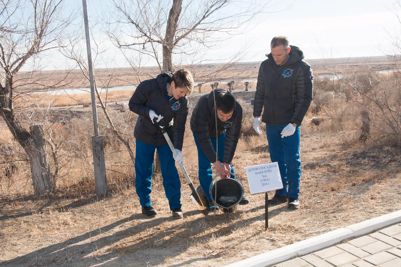jsc2018e097778 - At their Cosmonaut Hotel crew quarters in Baikonur, Kazakhstan, Expedition 58 crewmembers Anne McClain of NASA (left), Oleg Kononenko of Roscosmos (center)and David Saint-Jacques of the Canadian Space Agency (right) plant a tree in McClain’s name Nov. 27 as part of traditional pre-launch activities. They will launch Dec. 3 on the Soyuz MS-11 spacecraft from the Baikonur Cosmodrome in Kazakhstan for a six-and-a-half month mission on the International Space Station...NASA/Victor Zelentsov.