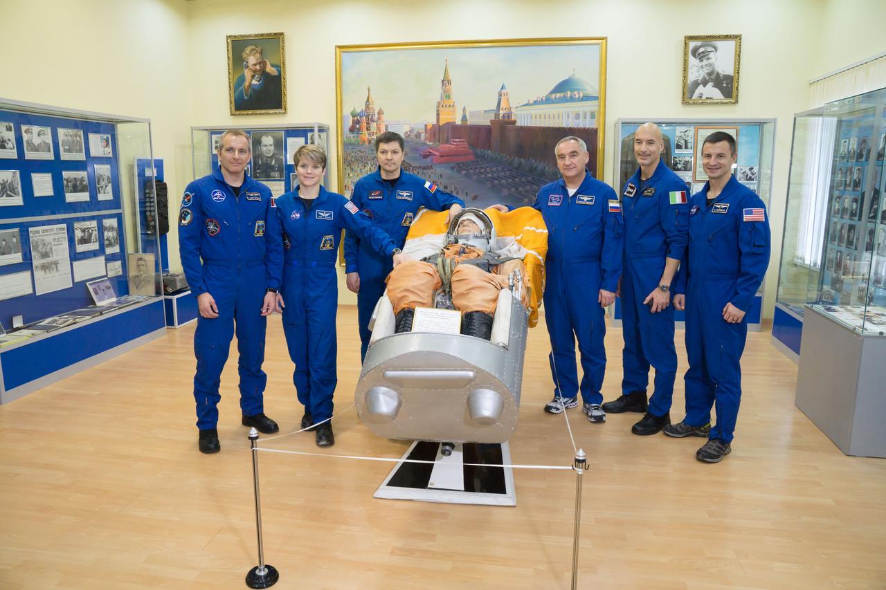 jsc2018e098095 - At the Baikonur Cosmodrome Museum in Kazakhstan, the Expedition 58 prime and backup crewmembers pose for pictures Nov. 29 around a mockup of a cosmonaut in a Soyuz spacecraft seat during a tour of the facility. From left to right are the prime crewmembers David Saint-Jacques of the Canadian Space Agency, Anne McClain of NASA and Oleg Kononenko of Roscosmos and the backup crew, Alexander Skvortsov of Roscosmos, Luca Parmitano of the European Space Agency and Drew Morgan of NASA. McClain, Saint-Jacques and Kononenko will launch Dec. 3 in the Soyuz MS-11 spacecraft from the Baikonur Cosmodrome in Kazakhstan for a six-and-a-half month mission on the International Space Station...NASA/Victor Zelentsov.