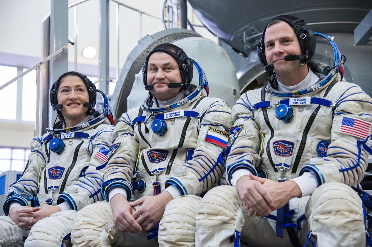 jsc2019e004067 (Feb. 20, 2019) --- At the Gagarin Cosmonaut Training Center in Star City, Russia, Expedition 59 crewmembers Christina Koch of NASA (left), Alexey Ovchinin of Roscosmos (center) and Nick Hague of NASA (right) listen to reporters’ questions in front of their Soyuz spacecraft simulator Feb. 20 during the second day of final pre-launch qualifications exams. They will launch March 14, U.S. time, in the Soyuz MS-12 spacecraft from the Baikonur Cosmodrome in Kazakhstan for a six-and-a-half month mission on the International Space Station. Credit: NASA/Beth Weissinger