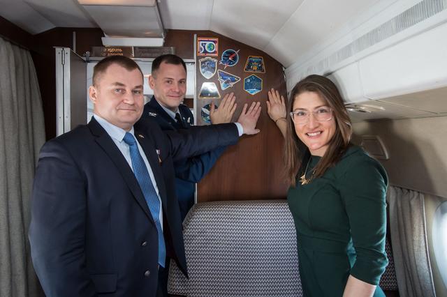 NASA image: jsc2019e007199 - Aboard a Gagarin Cosmonaut Training Center aircraft, Expedition 59 crewmembers Alexey Ovchinin of Roscosmos (left), Nick Hague of NASA (center) and Christina Koch of NASA (right) display crew insignia stickers on the wall of the cabin Feb