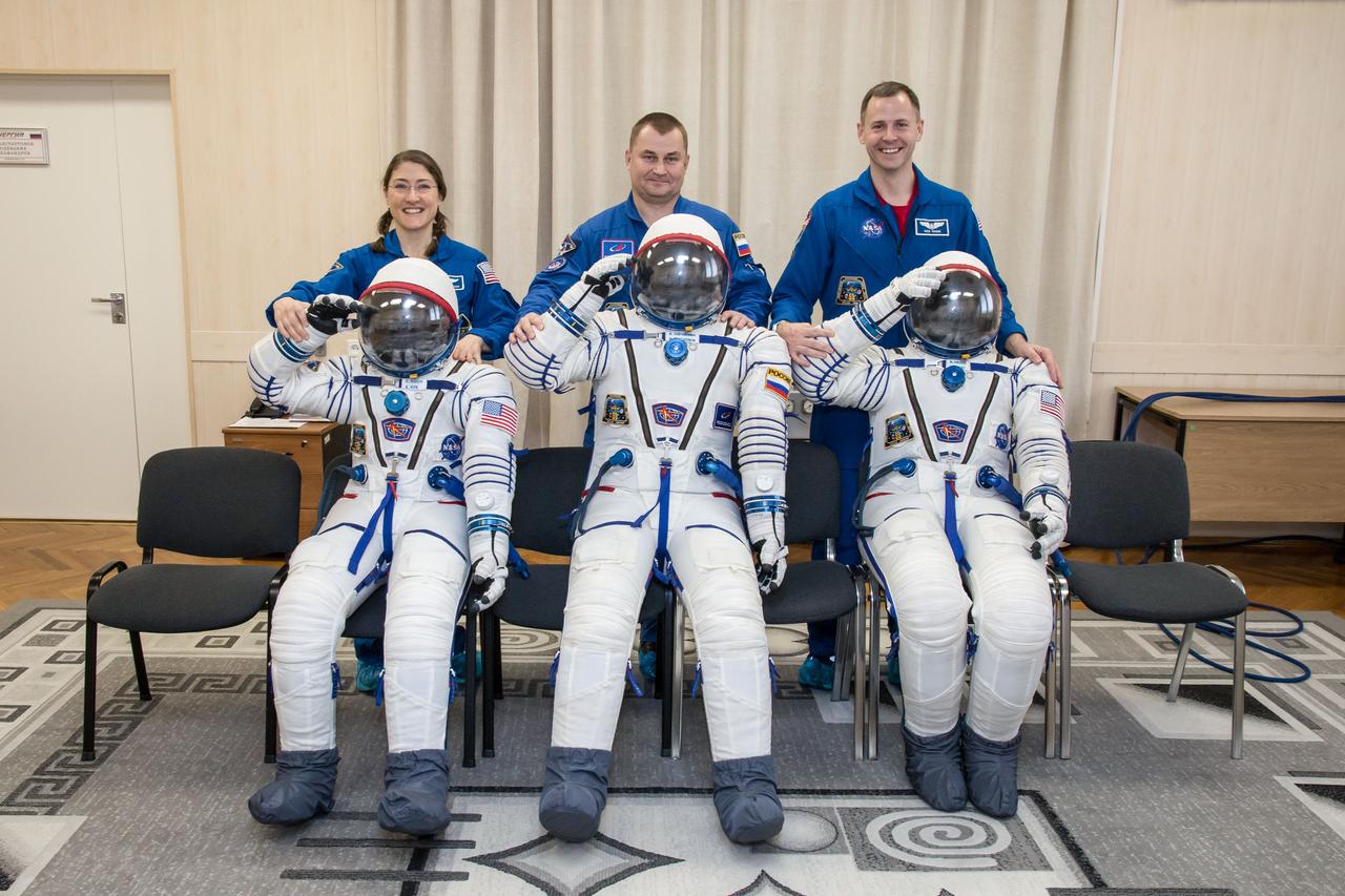 At the Baikonur Cosmodrome in Kazakhstan Expedition 59 crewmembers Christina Koch of NASA (left), Alexey Ovchinin of Roscosmos (center) and Nick Hague of NASA (right) share a playful moment with their Sokol launch and entry suits Feb. 27 after completing the first of two Soyuz spacecraft fit checks during pre-launch training. They will launch March 14, U.S. time, on the Soyuz MS-12 spacecraft from the Baikonur Cosmodrome in Kazakhstan for a six-and-a-half month mission on the International Space Station.  NASA/Victor Zelentsov 
