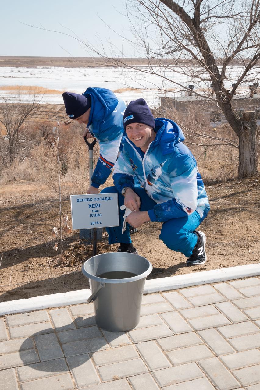 At the Cosmonaut Hotel crew quarters in Baikonur, Kazakhstan, Expedition 59 crewmember Nick Hague of NASA poses for pictures March 7 in front of a tree he originally planted last October before his first flight. Preparing the tree for watering is crewmate Alexey Ovchinin of Roscosmos. They launched together last October 11, but their flight was cut short two minutes after launch by an abort triggered by a first-stage booster rocket separation problem. They are set to launch again March 14, U.S. time, this time with crewmate Christina Koch of NASA on the Soyuz MS-12 spacecraft from the Baikonur Cosmodrome for a six-and-a-half month mission on the International Space Station...NASA/Victor Zelentsov.