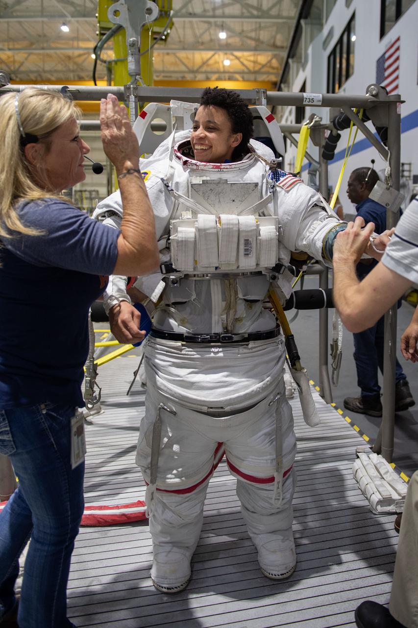 jsc2019e030012 (05-22-19) --- 2017 NASA astronaut candidate Jessica Watkins is helped into a spacesuit prior to underwater spacewalk training at NASA Johnson Space Center’s Neutral Buoyancy Laboratory in Houston. Photo Credit: (NASA/David DeHoyos)