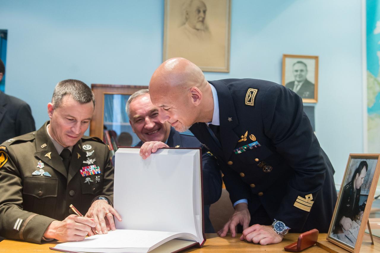 jsc2019e036813 - At the Gagarin Cosmonaut Training Center in Star City, Russia, Expedition 60 crewmember Drew Morgan of NASA (left) signs a ceremonial book June 28 during pre-launch activities. Looking on are crewmates Alexander Skvortsov of Roscosmos (center) and Luca Parmitano of the European Space Agency (right). Morgan, Parmitano and Skvortsov will launch July 20 on the Soyuz MS-13 spacecraft from the Baikonur Cosmodrome in Kazakhstan for a mission on the International Space Station...Andrey Shelepin/GCTC.