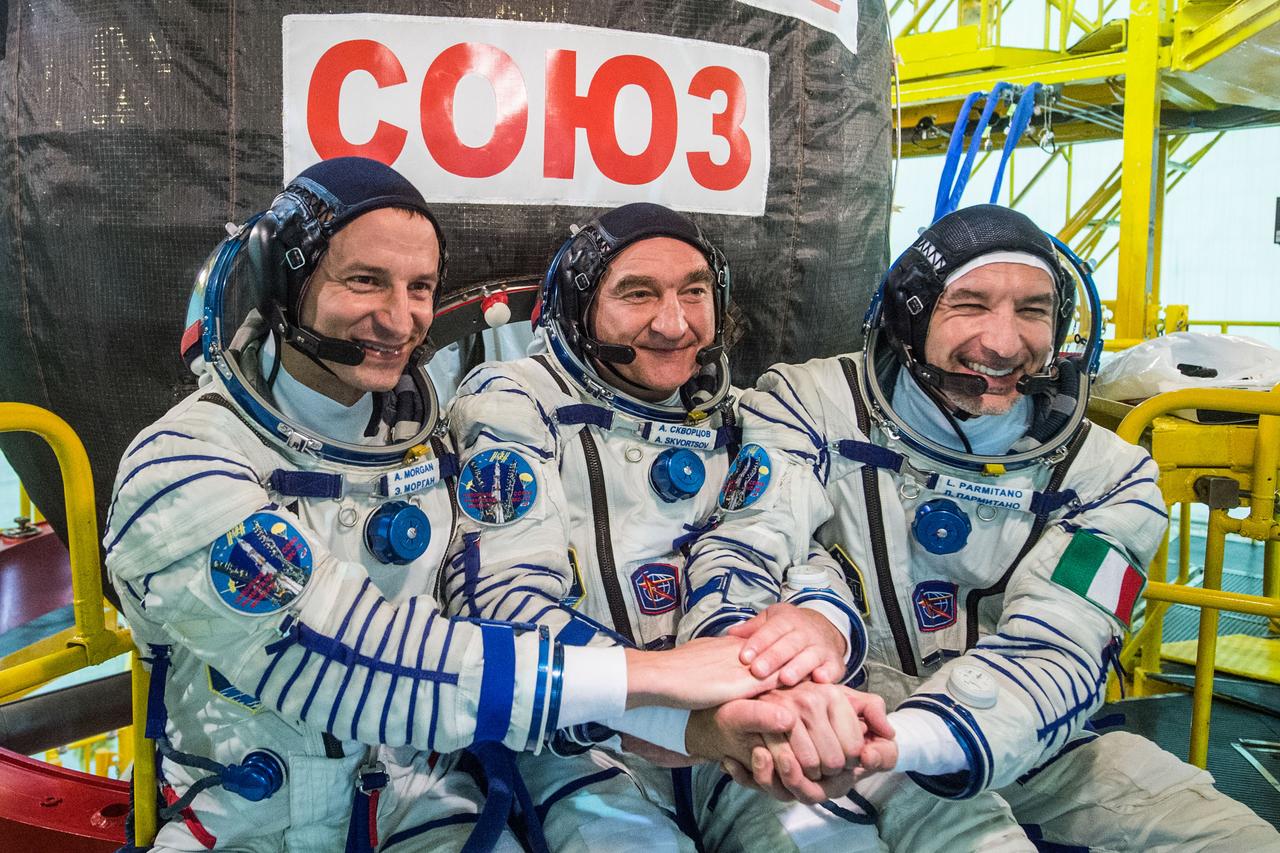 jsc2019e038381 - At the Baikonur Cosmodrome in Kazakhstan, Expedition 60 crewmembers Drew Morgan of NASA (left), Alexander Skvortsov of Roscosmos (center) and Luca Parmitano of the European Space Agency (right) pose for pictures July 5 in front of their Soyuz spacecraft during pre-launch preparations. They will launch July 20 on the Soyuz MS-13 spacecraft from the Baikonur Cosmodrome for a mission on the International Space Station...Andrey Shelepin/GCTC.