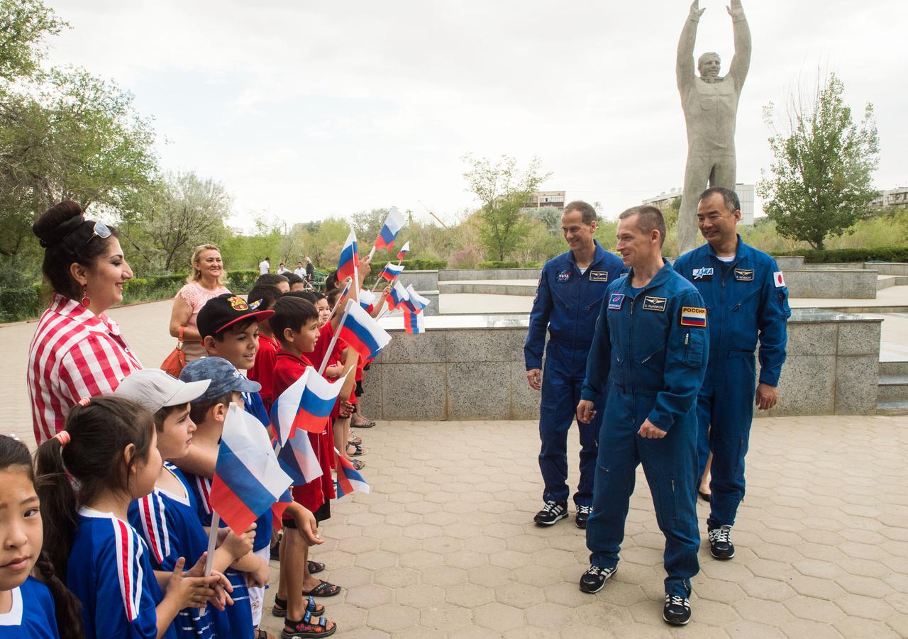 jsc2019e038392 - In the town of Baikonur, Kazakhstan, Expedition 60 backup crewmembers Tom Marshburn of NASA (left), Sergey Ryzhikov of Roscosmos (center) and Soichi Noguchi of the Japan Aerospace Exploration Agency (right) greet local school children July 6 near the statue of Yuri Gagarin, the first human to fly in space, during traditional pre-launch activities. They are the backups to Drew Morgan of NASA, Luca Parmitano of the European Space Agency and Alexander Skvortsov of Roscosmos, who will launch July 20 on the Soyuz MS-13 spacecraft from the Baikonur Cosmodrome in Kazakhstan for a mission on the International Space Station...Andrey Shelepin/GCTC.
