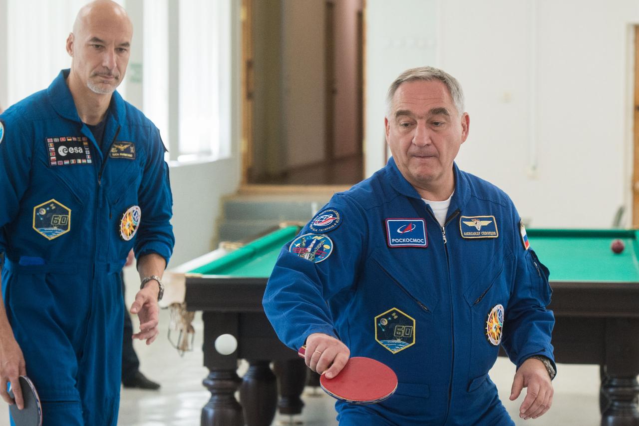 jsc2019e039258 - At the Cosmonaut Hotel crew quarters in Baikonur, Kazakhstan, Expedition 60 crewmember Alexander Skvortsov of Roscosmos (right) tries his hand at a game of ping-pong July 12 as crewmate Luca Parmitano of the European Space Agency (left) looks on. Skvortsov, Parmitano and Drew Morgan of NASA will launch July 20 on the Soyuz MS-13 spacecraft from the Baikonur Cosmodrome in Kazakhstan on a mission to the International Space Station...Andrey Shelepin/GCTC.