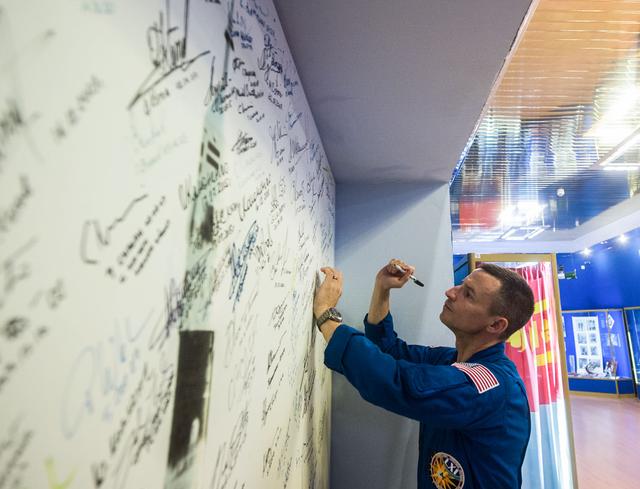 jsc2019e039428 - At the Baikonur Cosmodrome in Kazakhstan, Expedition 60 crewmember Drew Morgan of NASA signs a wall mural July 16 as part of pre-launch preparations. Morgan, Luca Parmitano of the European Space Agency and Alexander Skvortsov of Roscosmos will launch July 20 on the Soyuz MS-13 spacecraft from the Baikonur Cosmodrome for a mission on the International Space Station...Andrey Shelepin/GCTC.