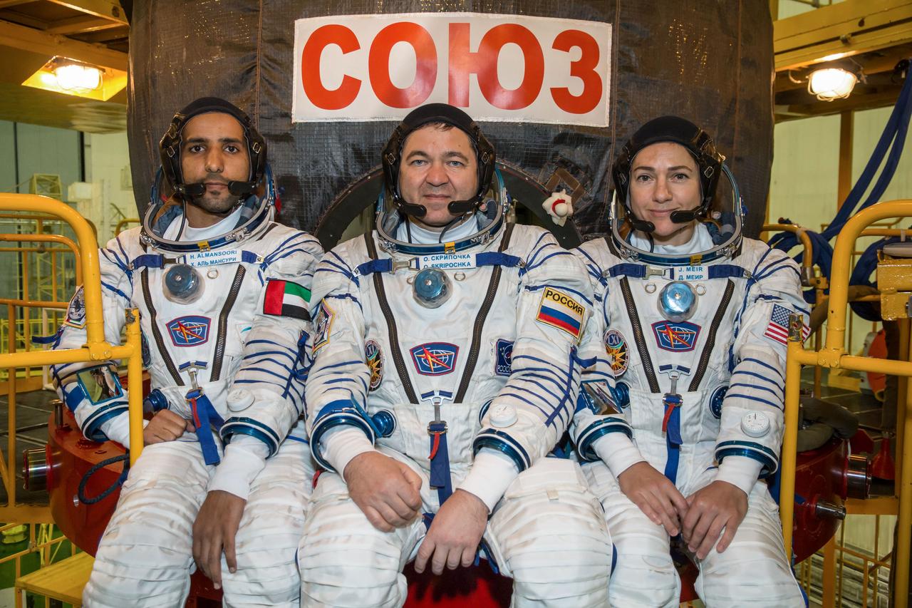 jsc2019e052891 - In the Integration Building at the Baikonur Cosmodrome in Kazakhstan, spaceflight participant Hazzaa Ali Almansoori of the United Arab Emirates (left) and Expedition 61 crewmates Oleg Skripochka of Roscosmos (center) and Jessica Meir of NASA (right) pose for pictures Sept. 11 in front of their Soyuz MS-15 spacecraft. They will launch Sept. 25 on the Soyuz MS-15 spacecraft from the Baikonur Cosmodrome for a mission on the International Space Station...NASA/Victor Zelentsov.