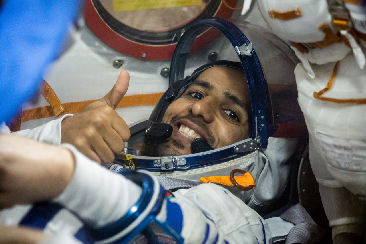 jsc2019e052893 - In the Integration Building at the Baikonur Cosmodrome in Kazakhstan, spaceflight participant Hazzaa Ali Almansoori of the United Arab Emirates flashes a thumbs up as he runs through procedures Sept. 11 aboard the Soyuz MS-15 spacecraft during an initial Soyuz vehicle fit check. Almansoori, Oleg Skripochka of Roscosmos and Jessica Meir of NASA will launch Sept. 25 on the Soyuz MS-15 spacecraft from the Baikonur Cosmodrome for a mission on the International Space Station...NASA/Victor Zelentsov.