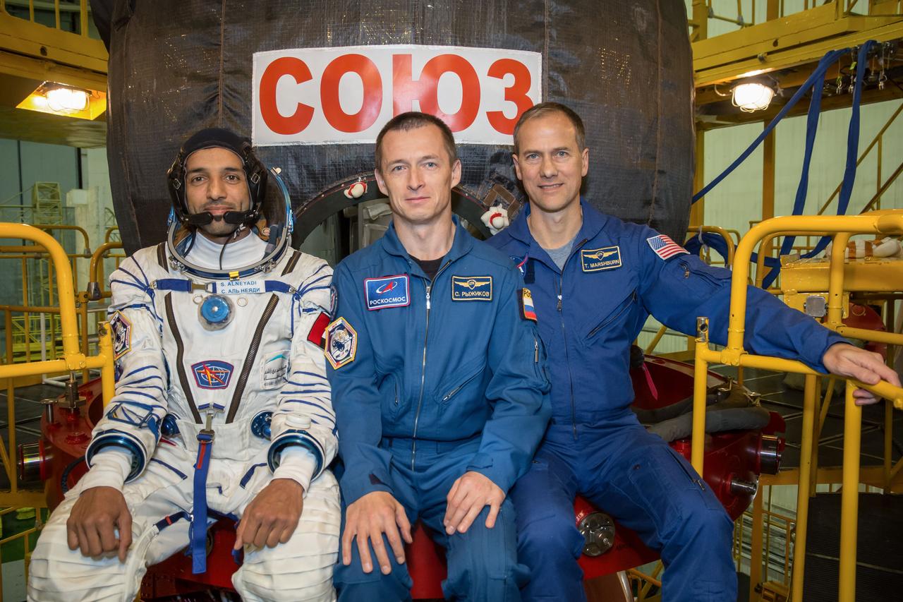 In the Integration Building at the Baikonur Cosmodrome in Kazakhstan, backup spaceflight participant Sultan Al-Neyadi of the United Arab Emirates (left) and backup Expedition 61 crewmates Sergey Ryzhikov of Roscosmos (center) and Tom Marshburn of NASA (right) pose for pictures Sept. 11 in front of the Soyuz MS-15 spacecraft. They are the backups to the prime crew, spaceflight participant Hazzaa Ali Almansoori of the United Arab Emirates and Expedition 61 crewmembers Oleg Skripochka of Roscosmos and Jessica Meir of NASA, who will launch Sept. 25 on the Soyuz MS-15 spacecraft from the Baikonur Cosmodrome for a mission on the International Space Station.  NASA/Victor Zelentsov 