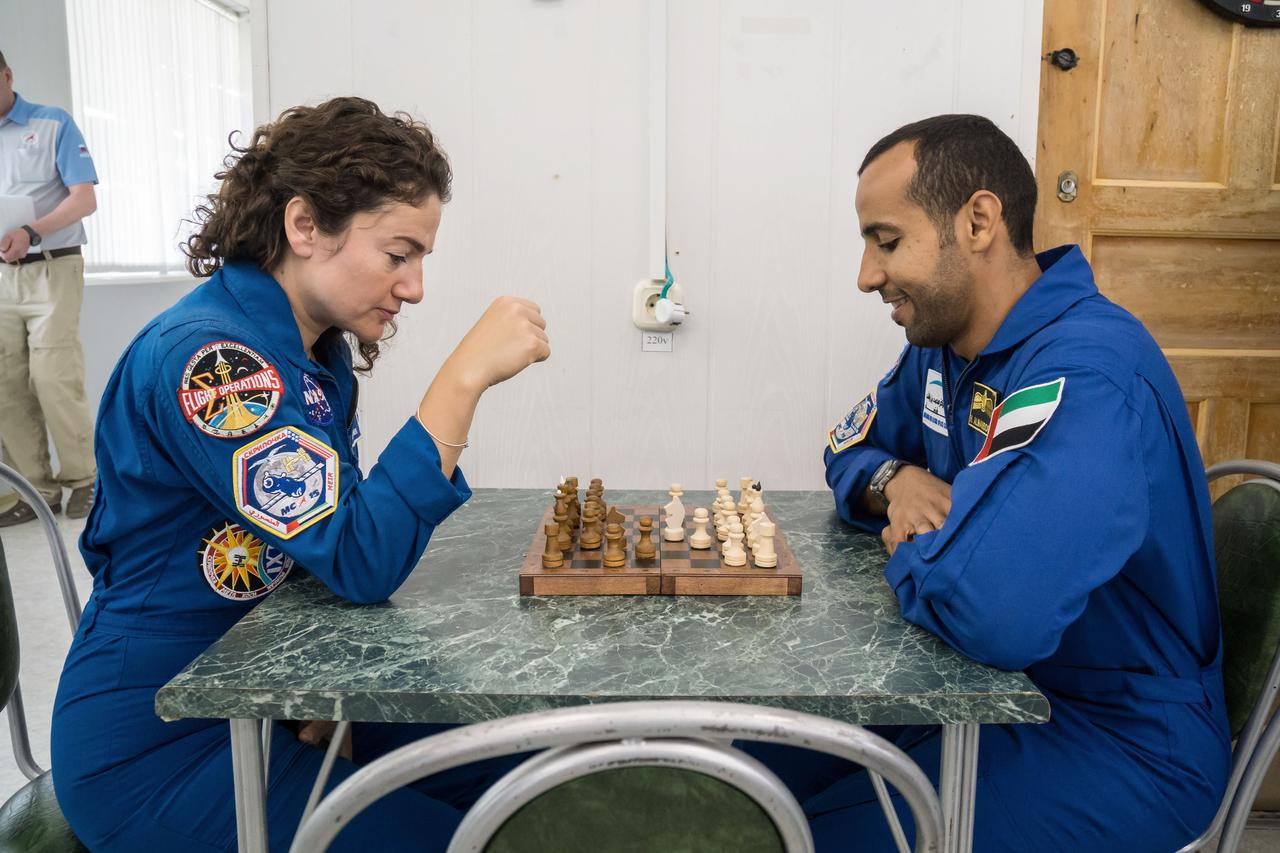 jsc2019e053719 - At the Cosmonaut Hotel crew quarters in Baikonur, Kazakhstan, Expedition 61 crewmember Jessica Meir of NASA (left) and spaceflight participant Hazzaa Ali Almansoori of the United Arab Emirates (right) share a game of chess Sept. 18 as part of pre-launch activities. Along with Oleg Skripochka of Roscosmos, they will launch Sept. 25 from the Baikonur Cosmodrome in Kazakhstan on the Soyuz MS-15 spacecraft for a mission on the International Space Station...NASA/Victor Zelentsov