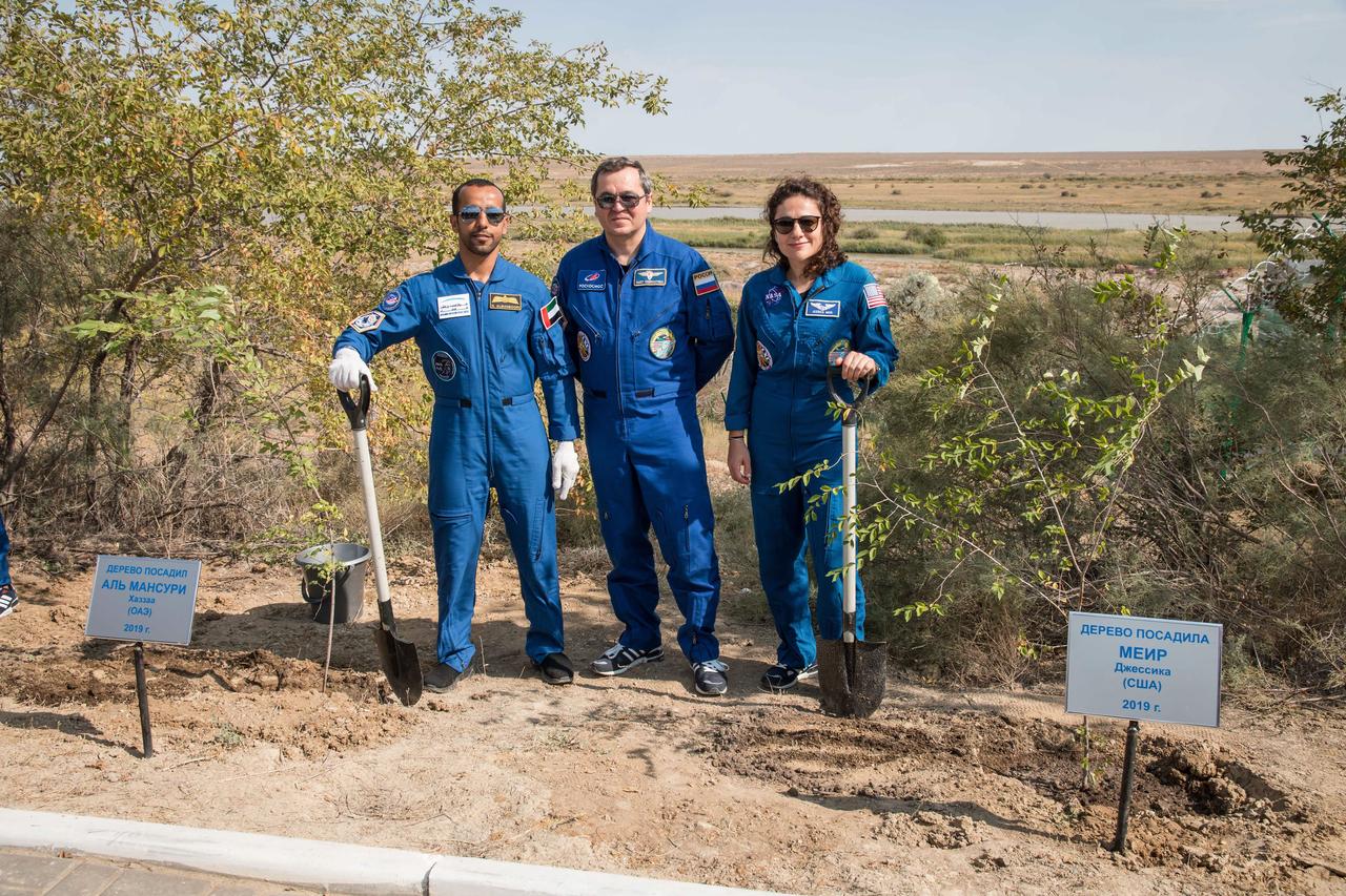 jsc2019e053726 - At the Cosmonaut Hotel crew quarters in Baikonur, Kazakhstan, spaceflight participant Hazzaa Ali Almansoori of the United Arab Emirates (left) and Expedition 61 crewmember Jessica Meir of NASA (right) pose for pictures Sept. 18 after planting trees in their names in a traditional pre-launch activity. Joined by Expedition 61 crewmember Oleg Skripochka of Roscosmos (center), they will launch Sept. 25 from the Baikonur Cosmodrome in Kazakhstan on the Soyuz MS-15 spacecraft for a mission on the International Space Station...NASA/Victor Zelentsov