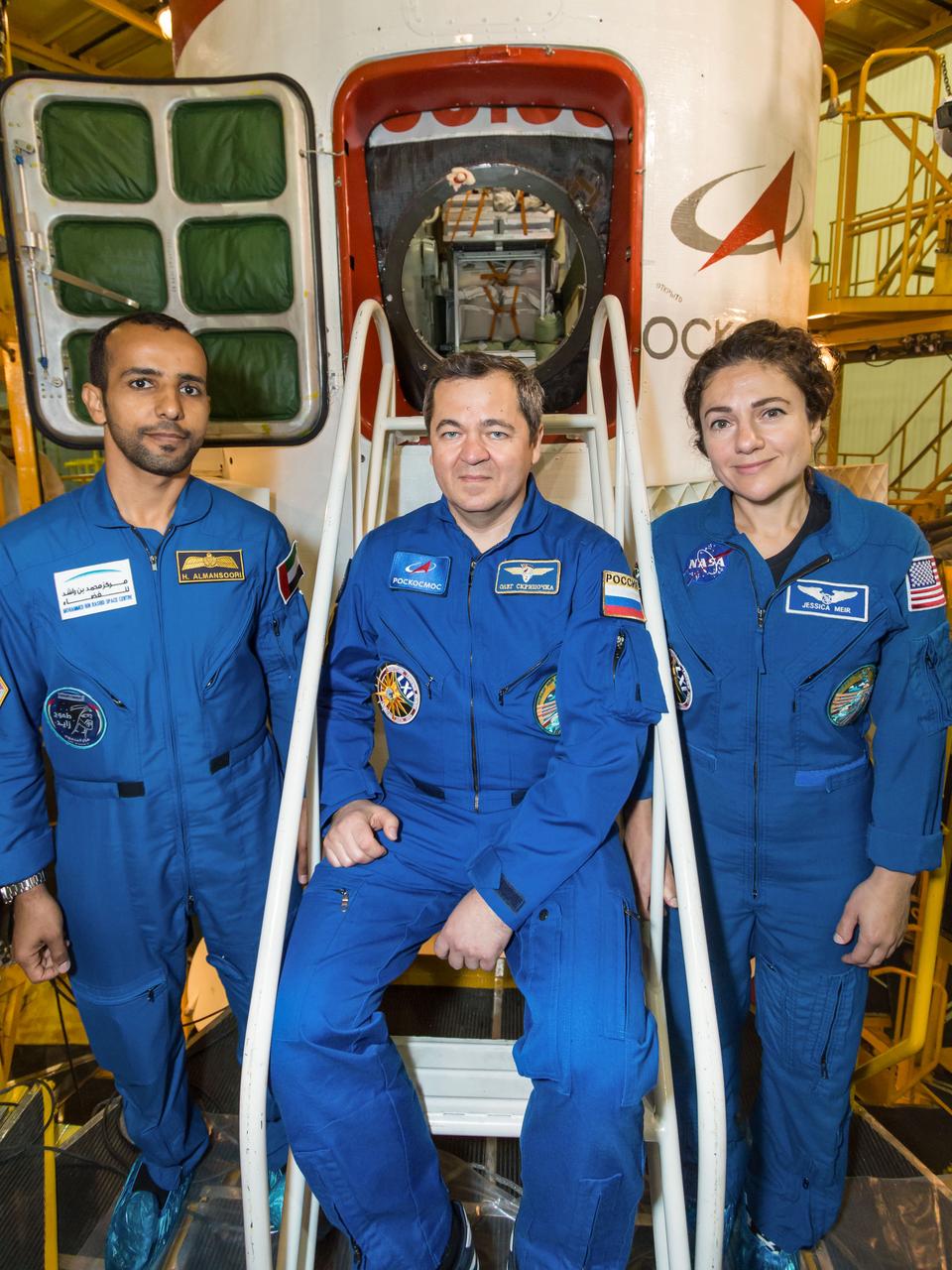 jsc2019e053737 - At the Baikonur Cosmodrome in Kazakhstan, spaceflight participant Hazzaa Ali Almansoori of the United Arab Emirates (left), Oleg Skripochka of Roscosmos (center) and Jessica Meir of NASA (right) pose for pictures in front of the Soyuz MS-15 spacecraft Sept. 20 during final fit check activities. They will launch Sept. 25 on the Soyuz MS-15 spacecraft for a mission on the International Space Station...NASA/Victor Zelentsov