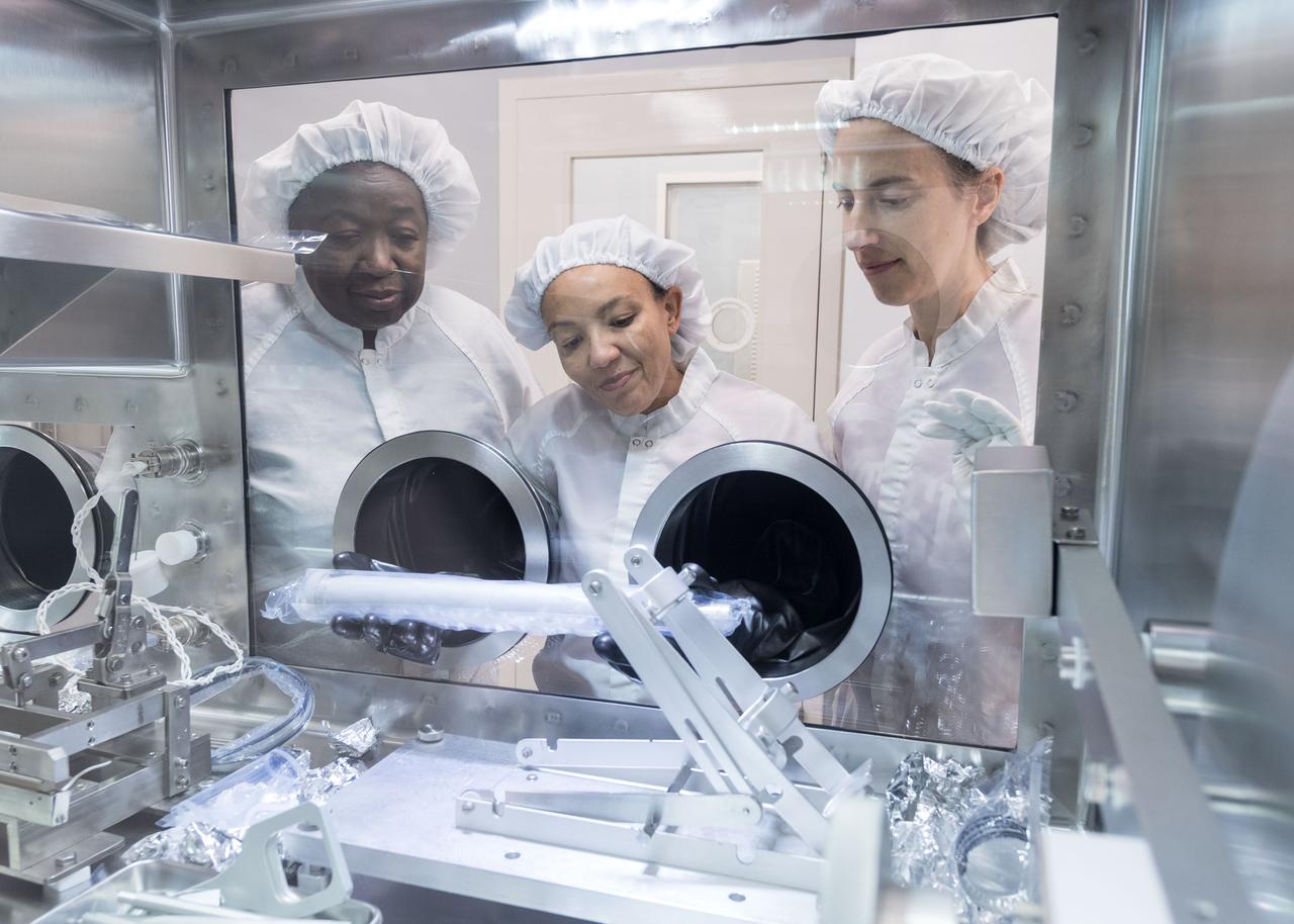jsc2019e063585 (Nov. 5, 2019) --- (From left) Andria Mosie, Charis Krysher and Juliane Gross, lunar sample curators, positioning the Apollo 17 drive tube prior to removing from its teflon bag and extruding sample 73002 at NASA's Johnson Space Center. The extrusion, which occurred Nov. 5, 2019 at Johnson Space Center in Houston, was done as part of NASA’s Apollo Next-Generation Sample Analysis initiative