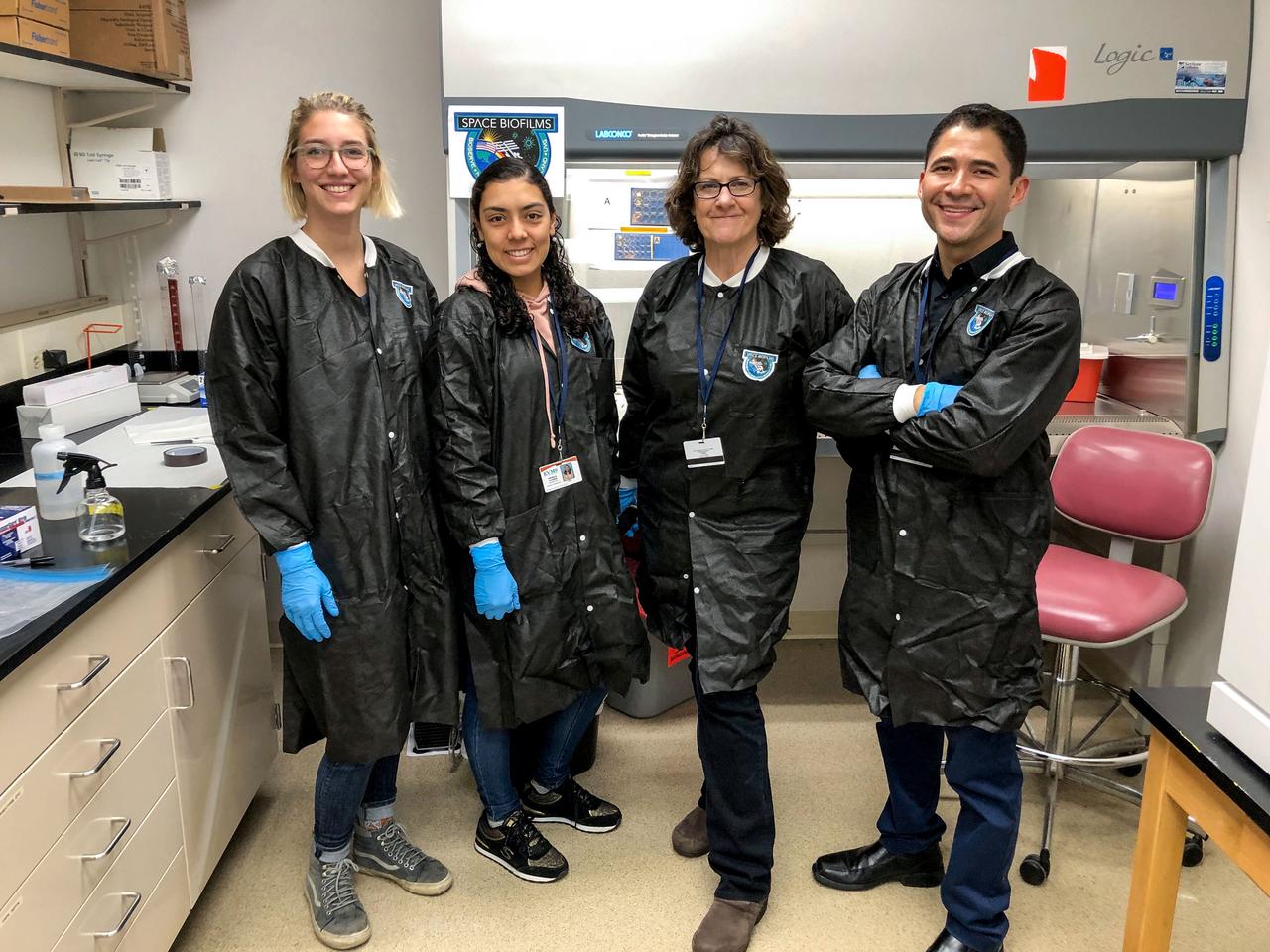 jsc2020e003402 (10/29/2019) --- The Space Bioflilms team, From left to right: University of Colorado, Boulder’s (CU) graduate students Rylee Schauer and Pamela Flores, Implementation Project Manager, BioServe’s Carla Hoehn, and the Principal Investigator, CU’s Luis Zea, Ph.D. The Characterization of Biofilm Formation, Growth, and Gene Expression on Different Materials and Environmental Conditions in Microgravity (Space Biofilms) investigation characterizes the mass, thickness, structure, and associated gene expression of biofilms that form in space by analyzing different microbial species grown on different materials. Biofilm formation can cause equipment malfunction and human illnesses, and could be a serious problem on future long-term human space missions.