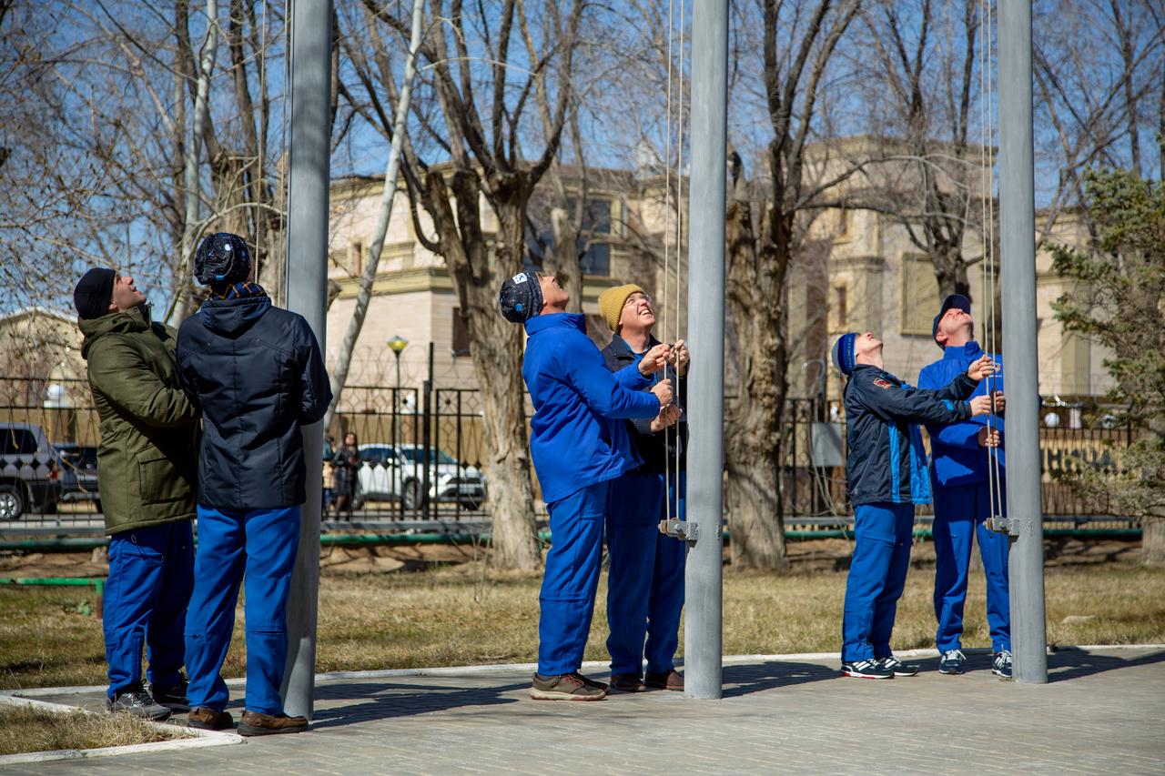 jsc2020e016865 - At the Cosmonaut Hotel crew quarters in Baikonur, Kazakhstan, the Expedition 63 prime and backup crewmembers raise the Russian, U.S. and Kazakh flags March 26 in a traditional ceremony. From left to right are prime crewmembers Ivan Vagner and Anatoly Ivanishin of Roscosmos, prime crewmember Chris Cassidy of NASA and his backup, Steve Bowen of NASA and backup crewmembers Sergey Ryzhikov and Andrei Babkin. Cassidy, Ivanishin and Vagner will launch April 9 from the Baikonur Cosmodrome on the Soyuz MS-16 spacecraft for a six-and-a-half month mission on the International Space Station...Courtesy/Roscosmos.