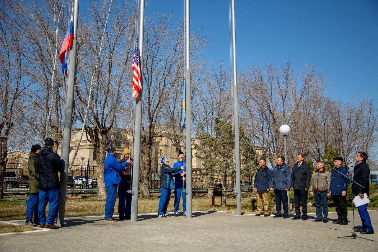 jsc2020e016867 - At the Cosmonaut Hotel crew quarters in Baikonur, Kazakhstan, the Expedition 63 prime and backup crewmembers raise the Russian, U.S. and Kazakh flags March 26 in a traditional ceremony. From left to right are prime crewmembers Ivan Vagner and Anatoly Ivanishin of Roscosmos, prime crewmember Chris Cassidy of NASA and his backup, Steve Bowen of NASA and backup crewmembers Sergey Ryzhikov and Andrei Babkin. Cassidy, Ivanishin and Vagner will launch April 9 from the Baikonur Cosmodrome on the Soyuz MS-16 spacecraft for a six-and-a-half month mission on the International Space Station...Courtesy/Roscosmos.