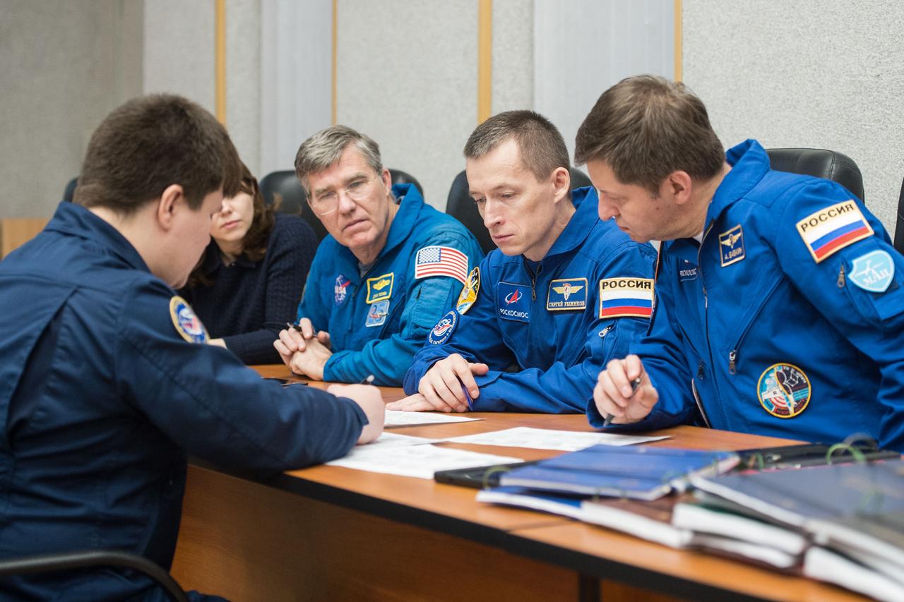 jsc2020e016954 - At the Cosmonaut Hotel crew quarters in Baikonur, Kazakhstan, Expedition 63 backup crewmembers Steve Bowen of NASA (left) and Sergey Ryzhikov (center) and Andrei Babkin (right) of Roscosmos review launch procedures with trainers April 1. They are the backups to the prime crew, Chris Cassidy of NASA and Anatoly Ivanishin and Ivan Vagner of Roscosmos, who will launch April 9 on the Soyuz MS-16 spacecraft from the Baikonur Cosmodrome in Kazakhstan for a six-and-a-half month mission on the International Space Station...Andrey Shelepin/Gagarin Cosmonaut Training Center.