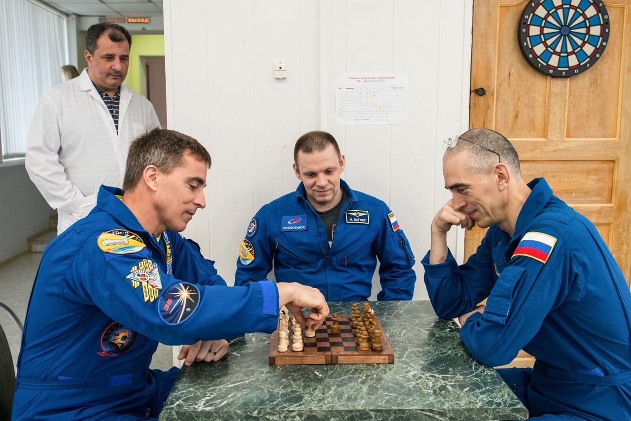 jsc2020e016960 - At the Cosmonaut Hotel crew quarters in Baikonur, Kazakhstan, Expedition 63 crewmembers Chris Cassidy of NASA (left) and Ivan Vagner (center) and Anatoly Ivanishin (right) of Roscosmos play a game of chess April 1. They are preparing to launch April 9 on the Soyuz MS-16 spacecraft from the Baikonur Cosmodrome in Kazakhstan for a six-and-a-half month mission on the International Space Station...Andrey Shelepin/Gagarin Cosmonaut Training Center.