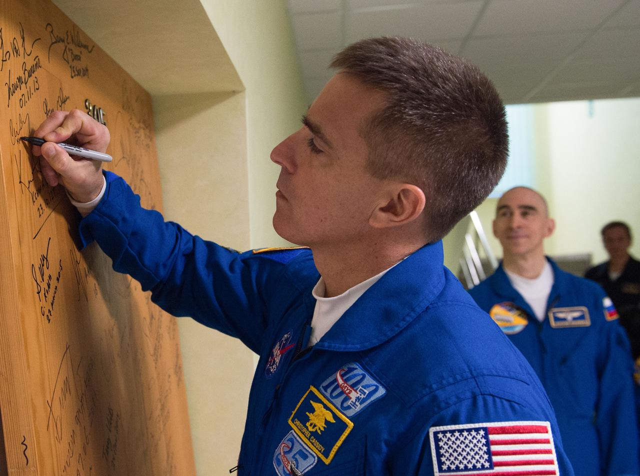 jsc2020e017064 - Expedition 63 Preflight - Expedition 63 crewmember Chris Cassidy of NASA signs a door in the Cosmonaut Hotel prior to departing for launch on a Soyuz rocket with Anatoly Ivanishin and Ivan Vagner of Roscosmos, Thursday, April 9, 2020 in Baikonur, Kazakhstan. The crew is beginning a six-and-a-half month mission on the International Space Station.  Photo Credit: (NASA/GCTC/Andrey Shelepin)