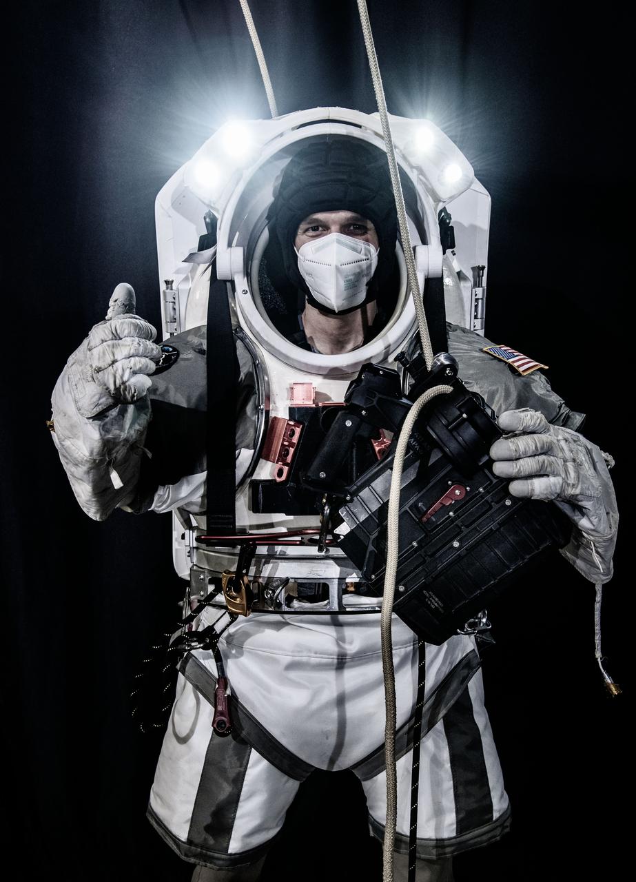 Nate Ball of Atlas Devices prepares to test an APA-5 powered rope ascender with the Exploration Conop (EXCON) Suit, a new xEMU spacesuit simulator.  Atlas uses this device in terrestrial applications of powered ascenders including rescue and vertical mobility.  This photo was taken when NASA began researching if these capabilities may have analogous applications for lunar surface operations. Photo Date: April 29, 2021. Location: Building 49 High Bay.  Photographer: Robert Markowitz