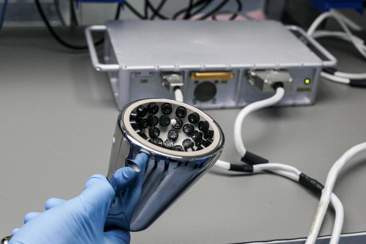 jsc2021e020422 (2/8/2021) --- A preflight view of the Ultrasonic Tweezers handle trapping a polystyrene sphere during hardware integration. Power supply box and control harness are visible on the background. The objective of the Ultrasonic Tweezers project is to develop acoustic tweezers that use sound to allow for remote and contactless manipulation of materials in a microgravity context. Image courtesy of CNES/S. Rouquette.
