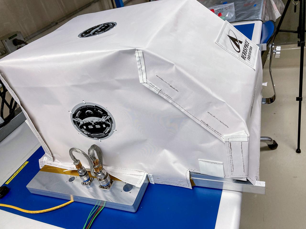 jsc2021e048046 (9/30/2021) --- Preflight imagery of the Intelligent Space System Interface Flight Qualification Experiment (iSSFIQE) with the Multi-layer Insulation (MLI) cover fully interfaced with the IVA-replaceable Small Exposed Experiment Platform (i-SEEP) ground model. Image courtesy of Skycorp Inc.