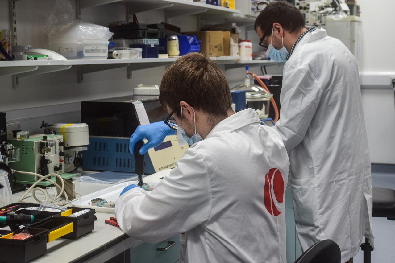 jsc2021e058714 (3/4/2021) --- The MicroAge experimental unit assembly at the University of Liverpool. Picture featuring Kayser Space Ltd (from left to right William Blackler and Gianluca Neri) at the Institute of Life Course and Medical Sciences. This investigation helps identify the mechanisms by which astronauts lose skeletal muscle mass in microgravity and identify optimum exercise regimens, nutritional, or pharmacological interventions for prevention. Image Courtesy of University of Liverpool.