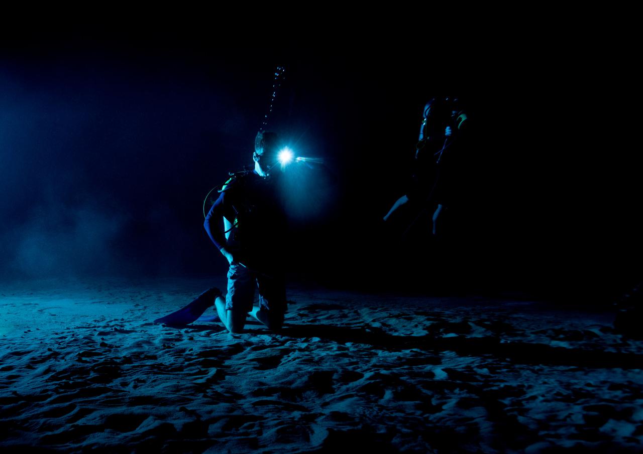 Test subjects performing subjective assessment of supplemental lighting during NBL Preliminary Lunar Lighting Evaluation.  Divers at the Neutral Buoyancy Laboratory (NBL) in Houston are setting the stage for future Moonwalk training by simulating lunar lighting conditions. At the Lunar South Pole, the Sun will remain no more than a few degrees above the horizon, resulting in extremely long and dark shadows. To prepare astronauts for these challenging lighting conditions, the team at the NBL has begun preliminary evaluations of lunar lighting solutions at the bottom of the 40-foot deep pool. This testing and evaluation involved turning off all the lights in the facility, installing black curtains on the pool walls to minimize reflections, and using a powerful underwater cinematic lamp, to get the conditions just right ahead of upcoming training for astronauts.