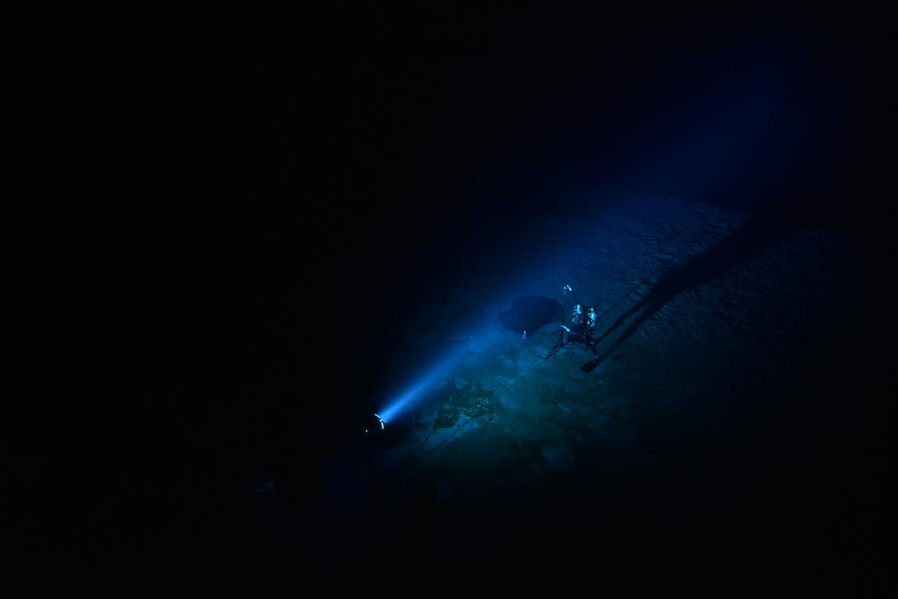 Quantitative evaluation of light source by NBL diver during NBL Preliminary Lunar Lighting Evaluation. Divers at the Neutral Buoyancy Laboratory (NBL) in Houston are setting the stage for future Moonwalk training by simulating lunar lighting conditions. At the Lunar South Pole, the Sun will remain no more than a few degrees above the horizon, resulting in extremely long and dark shadows. To prepare astronauts for these challenging lighting conditions, the team at the NBL has begun preliminary evaluations of lunar lighting solutions at the bottom of the 40-foot deep pool. This testing and evaluation involved turning off all the lights in the facility, installing black curtains on the pool walls to minimize reflections, and using a powerful underwater cinematic lamp, to get the conditions just right ahead of upcoming training for astronauts.