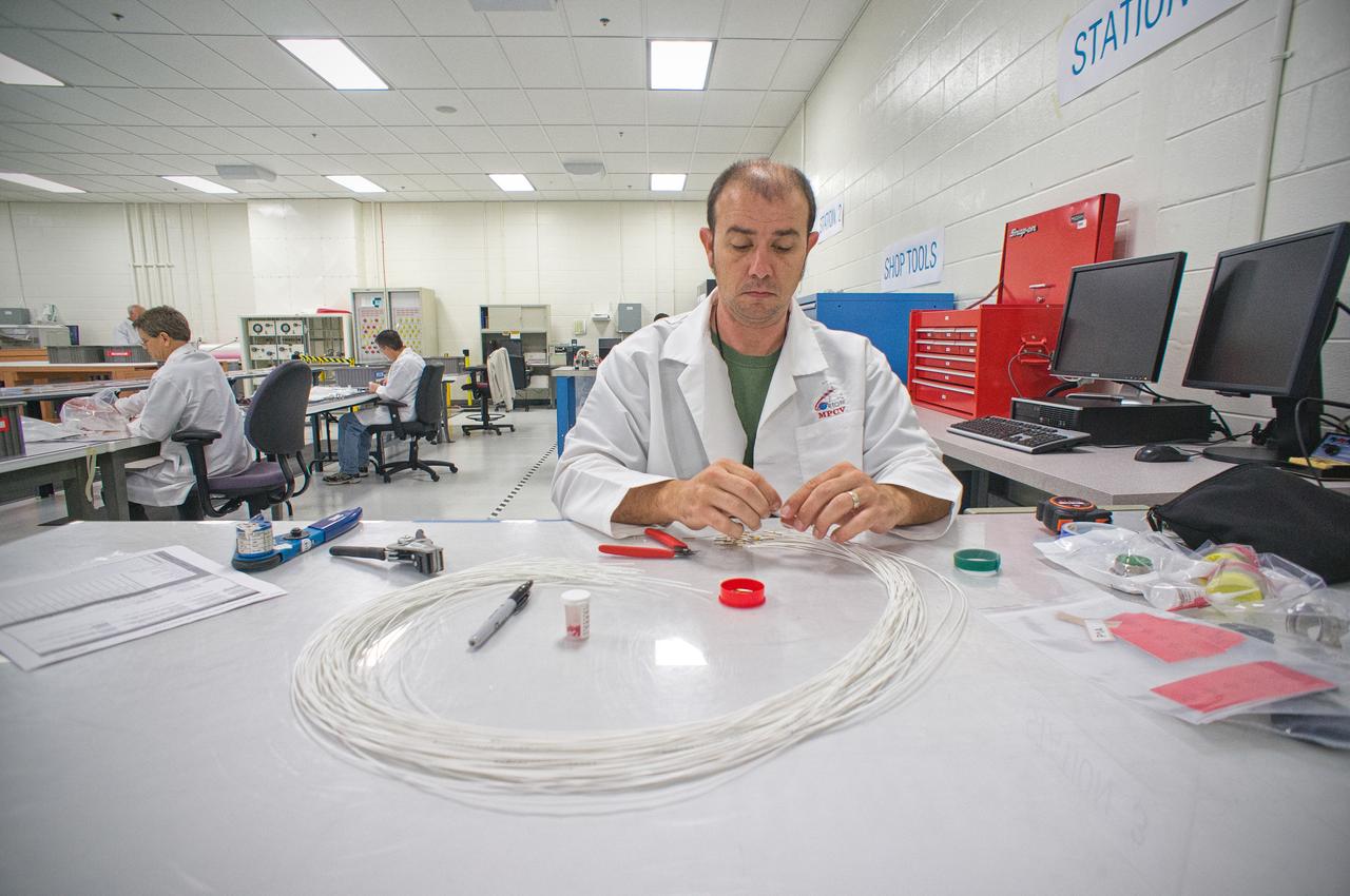 Technicians work on the harness assembly for the Exploration Flight Test-1 (EFT-1) Orion in the Operations and Checkout (O&amp;C) Building at NASA’s Kennedy Space Center on Jan. 1, 2012.  Part of Batch image transfer from Flickr. 