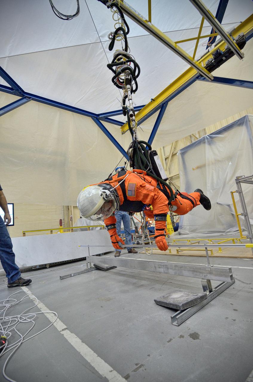 Astronaut Rex Walheim uses the Active Response Gravity Offload System (ARGOS) to perform early evaluations of the Orion Crew Survival System (OCSS) suit in Building 9 of Johnson Space Center in Houston on June 5, 2012. ARGOS is designed to simulate reduced gravity environments, such as lunar, Martian, or microgravity, using a system similar to an overhead bridge crane. Part of Batch image transfer from Flickr.