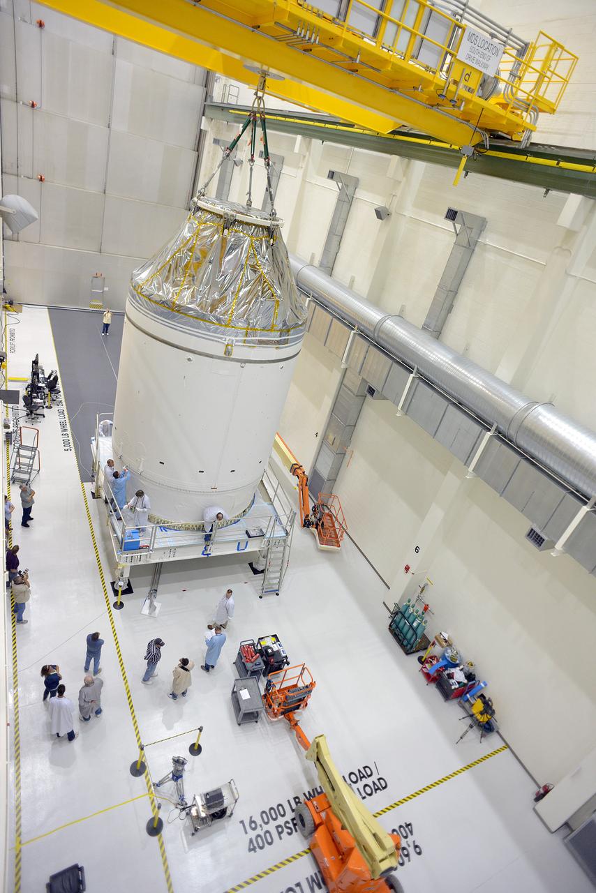 Technicians and engineers put finishing touches on the Orion Exploration Flight Test-1 (EFT-1) crew module and service module stack in the Operations and Checkout (O&amp;C) Building at Kennedy Space Center on Sept. 7, 2014. The crew module is covered by protective foil as it and the service module are lifted for the installation of the Orion-to-stage adapter ring. Part of Batch image transfer from Flickr.