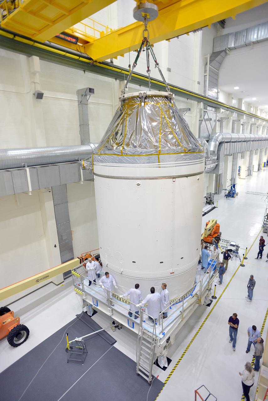 Technicians and engineers put finishing touches on the Orion Exploration Flight Test-1 (EFT-1) crew module and service module stack in the Operations and Checkout (O&amp;C) Building at Kennedy Space Center on Sept. 7, 2014. The crew module is covered by protective foil as it and the service module are lifted for the installation of the Orion-to-stage adapter ring. Part of Batch image transfer from Flickr.