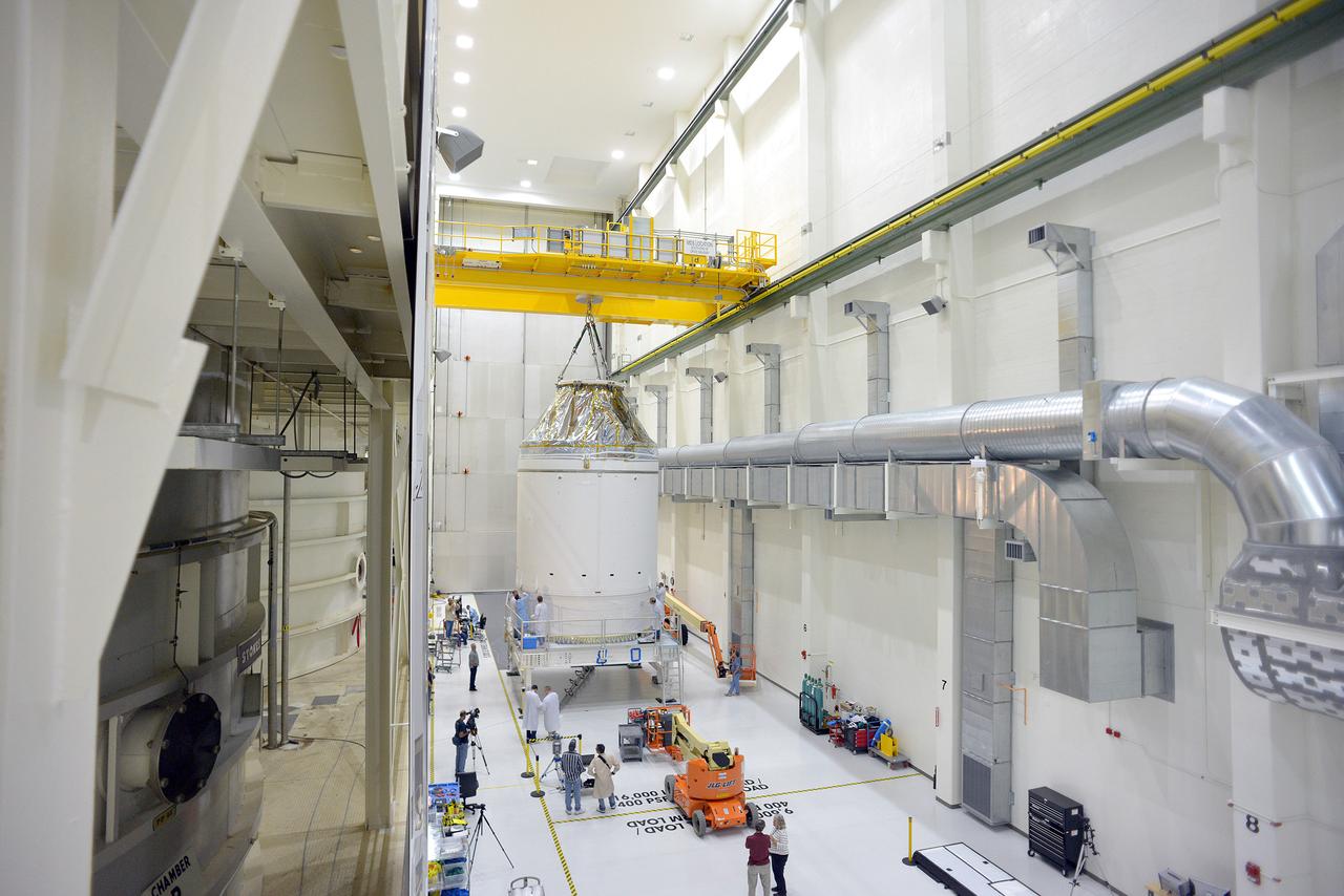 Technicians and engineers put finishing touches on the Orion Exploration Flight Test-1 (EFT-1) crew module and service module stack in the Operations and Checkout (O&amp;C) Building at Kennedy Space Center on Sept. 7, 2014. The crew module is covered by protective foil as it and the service module are lifted for the installation of the Orion-to-stage adapter ring. Part of Batch image transfer from Flickr.