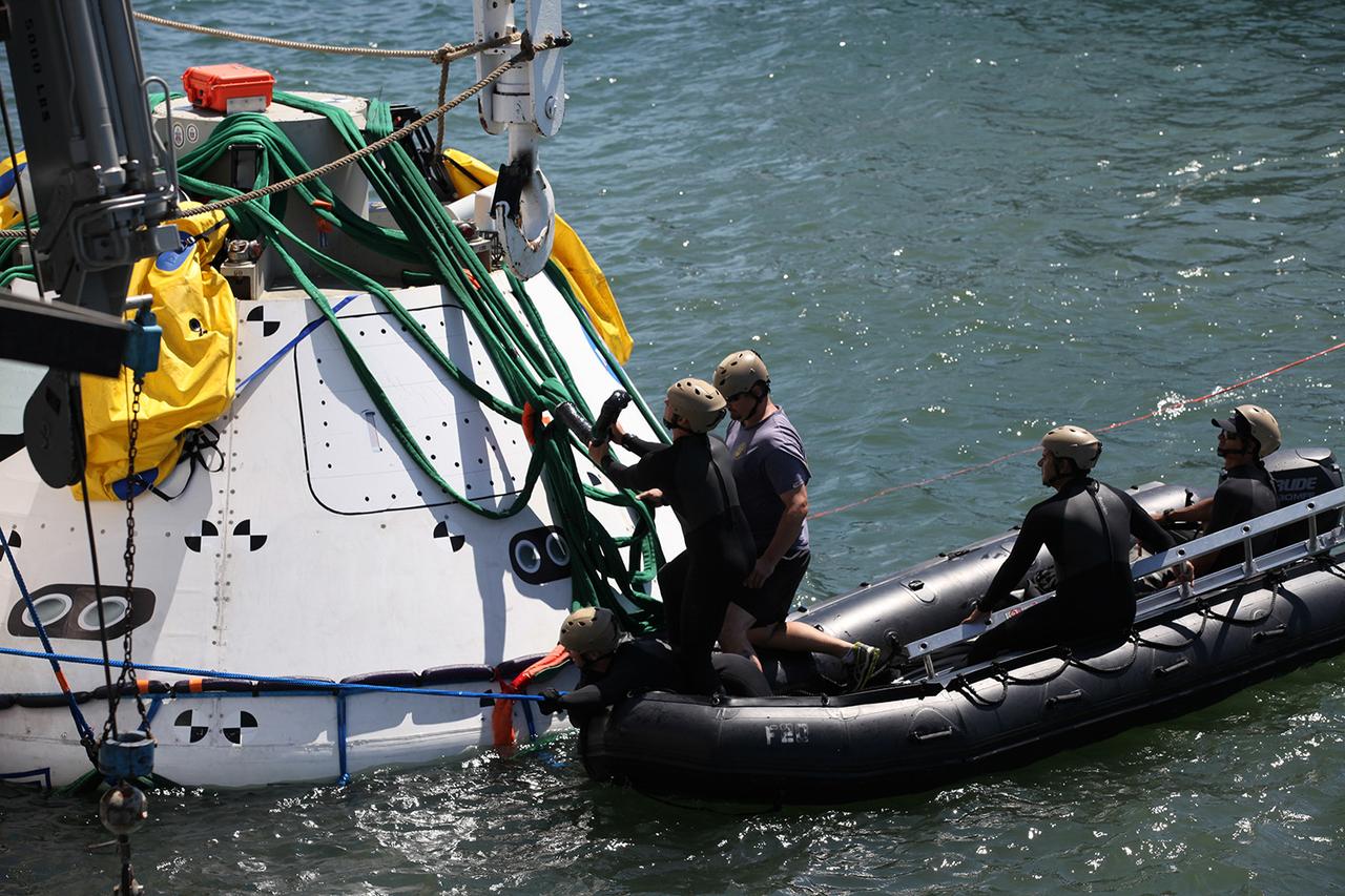 Recovery team members attach cables to a test version of Orion in the Pacific Ocean on Sept. 12, 2014. A combined NASA and U.S. Navy team practiced recovery techniques off the coast of California over the course of the next week -- first with the crane, as seen here, then using the USS Anchorage's well deck -- in preparation for Exploration Flight Test-1 (EFT-1). Part of Batch image transfer from Flickr.
