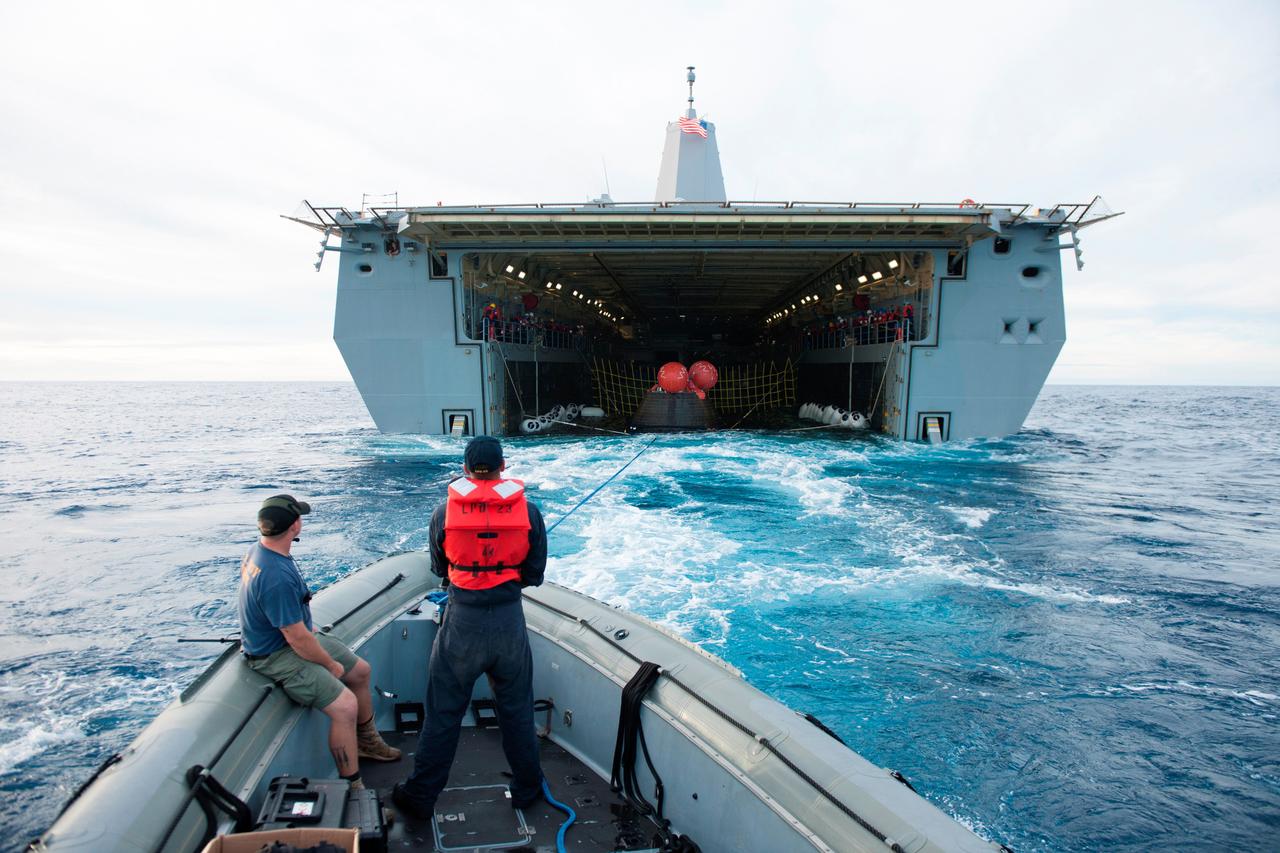 Recovery team members in a Zodiac boat help guide NASA's Orion spacecraft into the well deck of the USS Anchorage following its splashdown in the Pacific Ocean. Orion launched into space on a two-orbit, 4.5-test flight at 7:05 am EST on Dec. 5, and returned safely to Earth, where a combined team from NASA, the Navy and Orion prime contractor Lockheed Martin retrieved it for return to shore. It's now being transported back to shore on board the Anchorage. It is expected to be off loaded at Naval Base San Diego on Monday.  Part of Batch image transfer from Flickr.