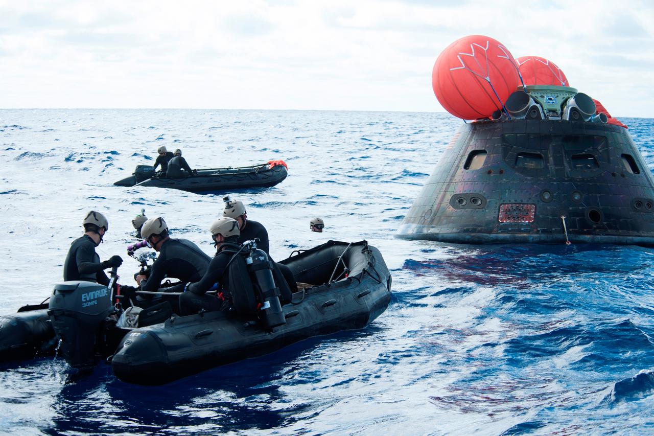 Recovery team members in rigid-hulled inflatable boats approach NASA's Orion spacecraft following its splashdown in the Pacific Ocean. Orion launched into space on a two-orbit, 4.5-test flight at 7:05 am EST on Dec. 5, and returned safely to Earth, where a combined team from NASA, the Navy and Orion prime contractor Lockheed Martin retrieved it for return to shore. It's now being transported back to shore on board the U.S. Navy's USS Anchorage. It is expected to be off loaded at Naval Base San Diego on Monday. Part of Batch image transfer from Flickr.