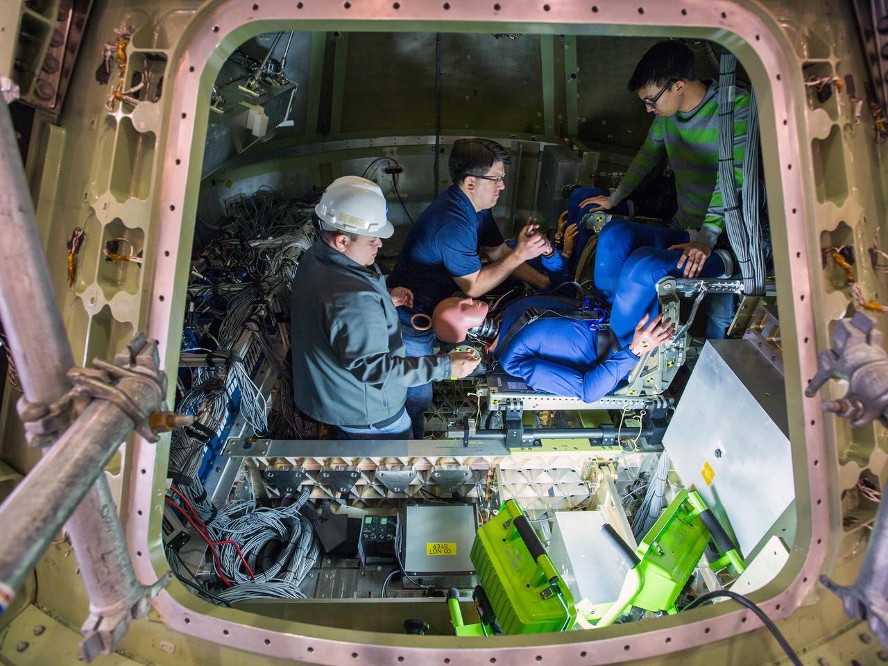 Engineers at NASA’s Langley Research Center in Hampton, Virginia, install test dummies into the seats of an Orion test article on Feb. 26, 2016. The capsule, coupled with the heat shield from the spacecraft’s first flight, will be used for water-impact testing to simulate what astronauts will experience when landing in the Pacific Ocean during a real mission.