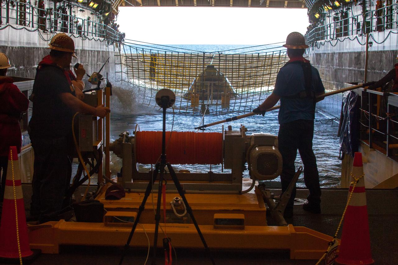 Winch team operators help guide a test version of the Orion crew module into the flooded well deck of the USS San Diego during Underway Recovery Test 5 in the Pacific Ocean off the coast of California. NASA's Ground Systems Development and Operations Program and the U.S. Navy are conducting a series of tests to prepare for recovery of Orion on its return from deep space missions. The testing will allow the team to demonstrate and evaluate recovery processes, procedures, hardware and personnel in open waters. Part of Batch images transfer from Flickr. 