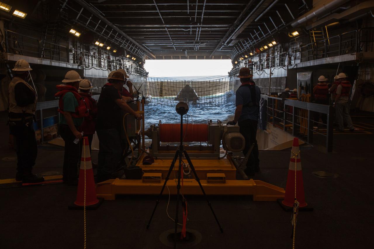 Winch team operators help guide a test version of the Orion crew module in the flooded well deck of the USS San Diego during Underway Recovery Test 5 in the Pacific Ocean off the coast of California on Oct. 29, 2016. NASA's Ground Systems Development and Operations Program and the U.S. Navy are conducting a series of tests using the ship's well deck, the test module, various watercraft and equipment to prepare for recovery of Orion on its return from deep space missions. The testing will allow the team to demonstrate and evaluate recovery processes, procedures, hardware and personnel in open waters. Part of Batch images transfer from Flickr. 